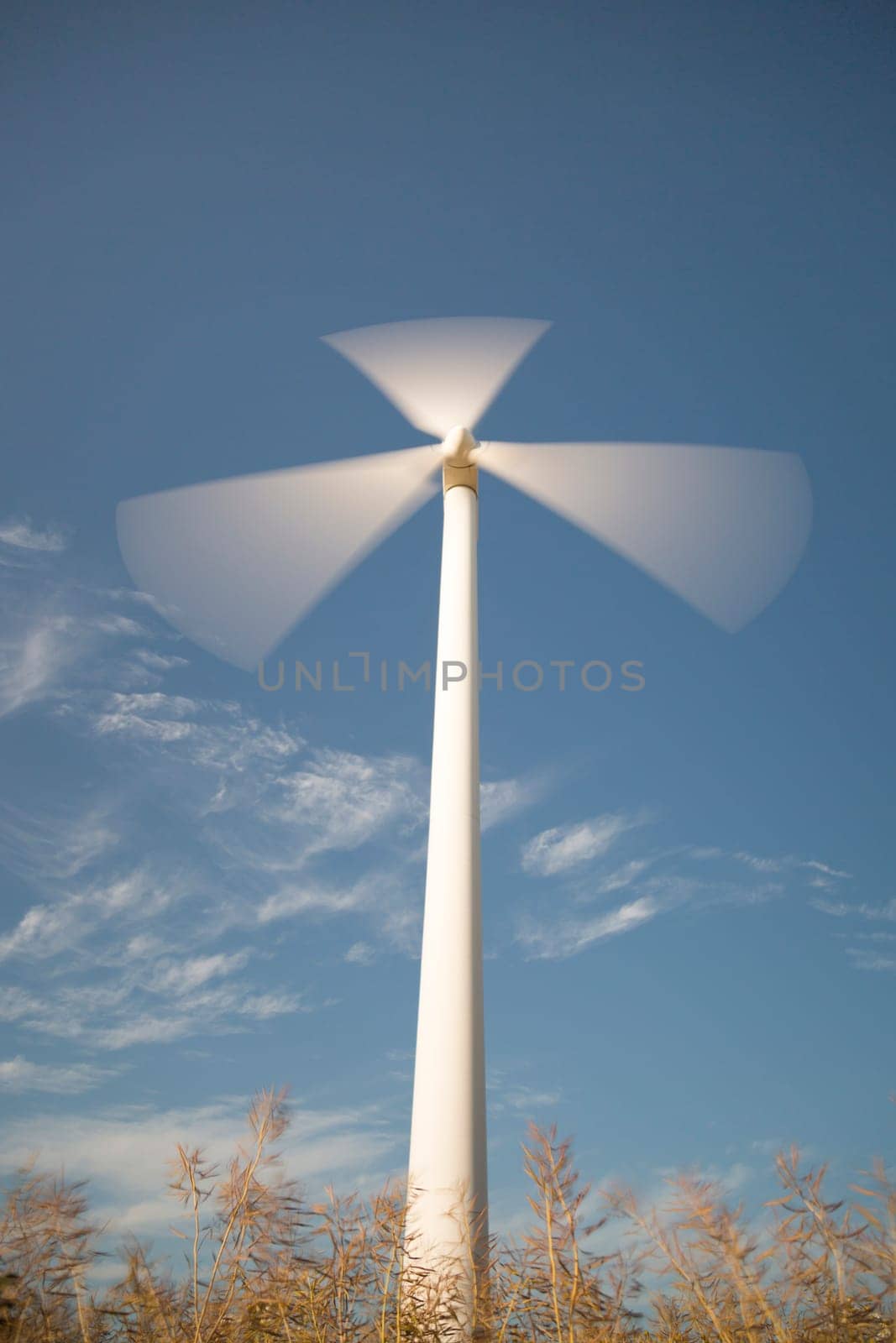 Wind Power Station Spinning Fast with blue sky and some clouds.