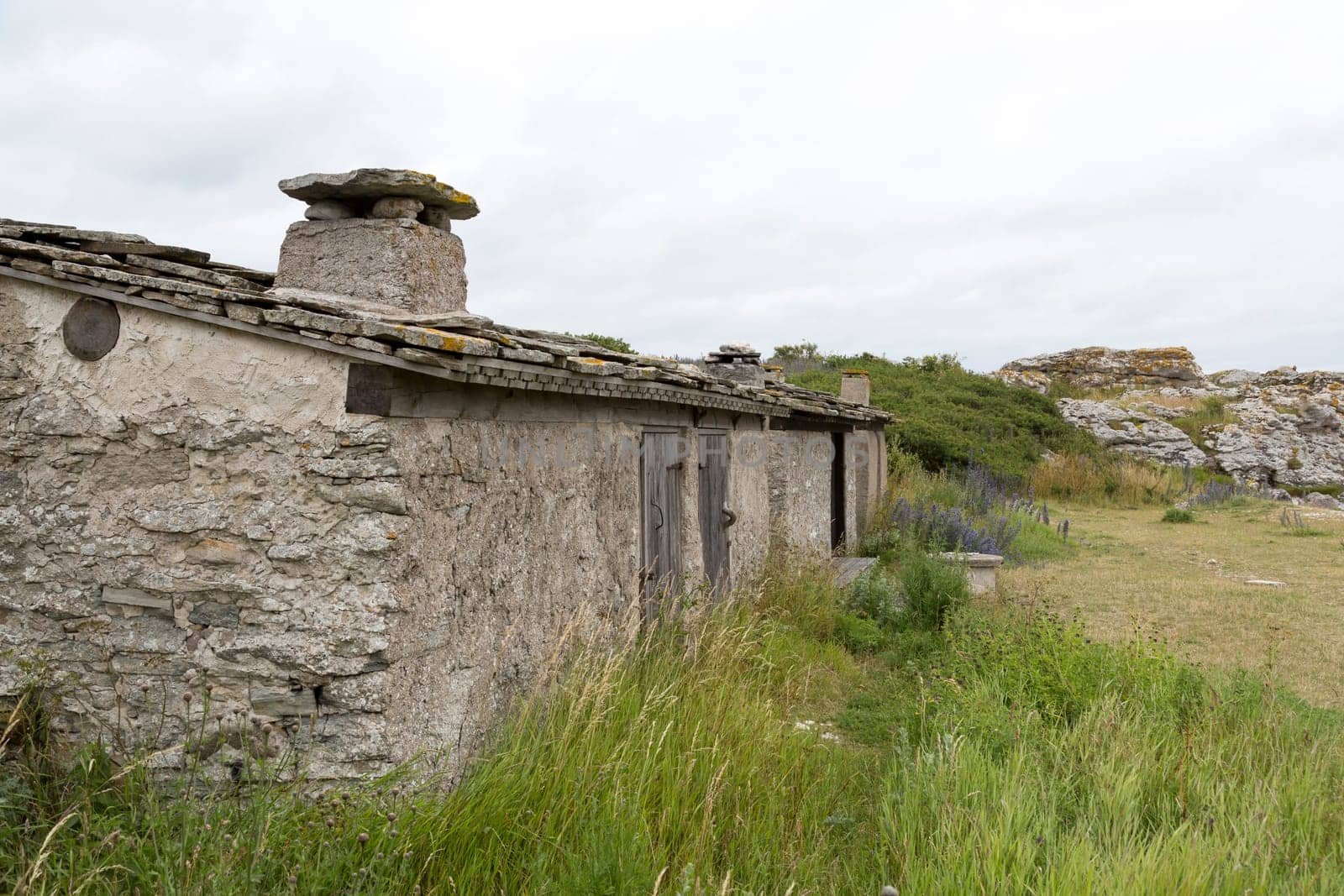 Old Fishing Hut in Gotland, Sweden with sea stacks next to it.