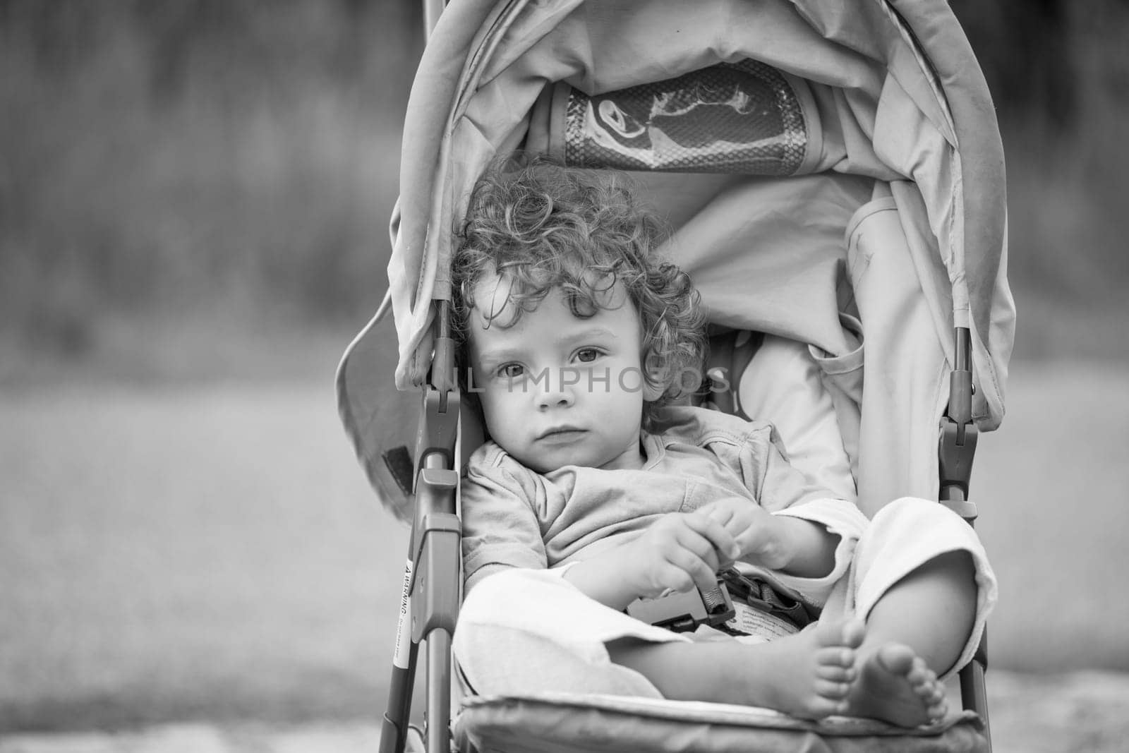 Portrait of 1 year old baby boy in the stroller, black and white image.