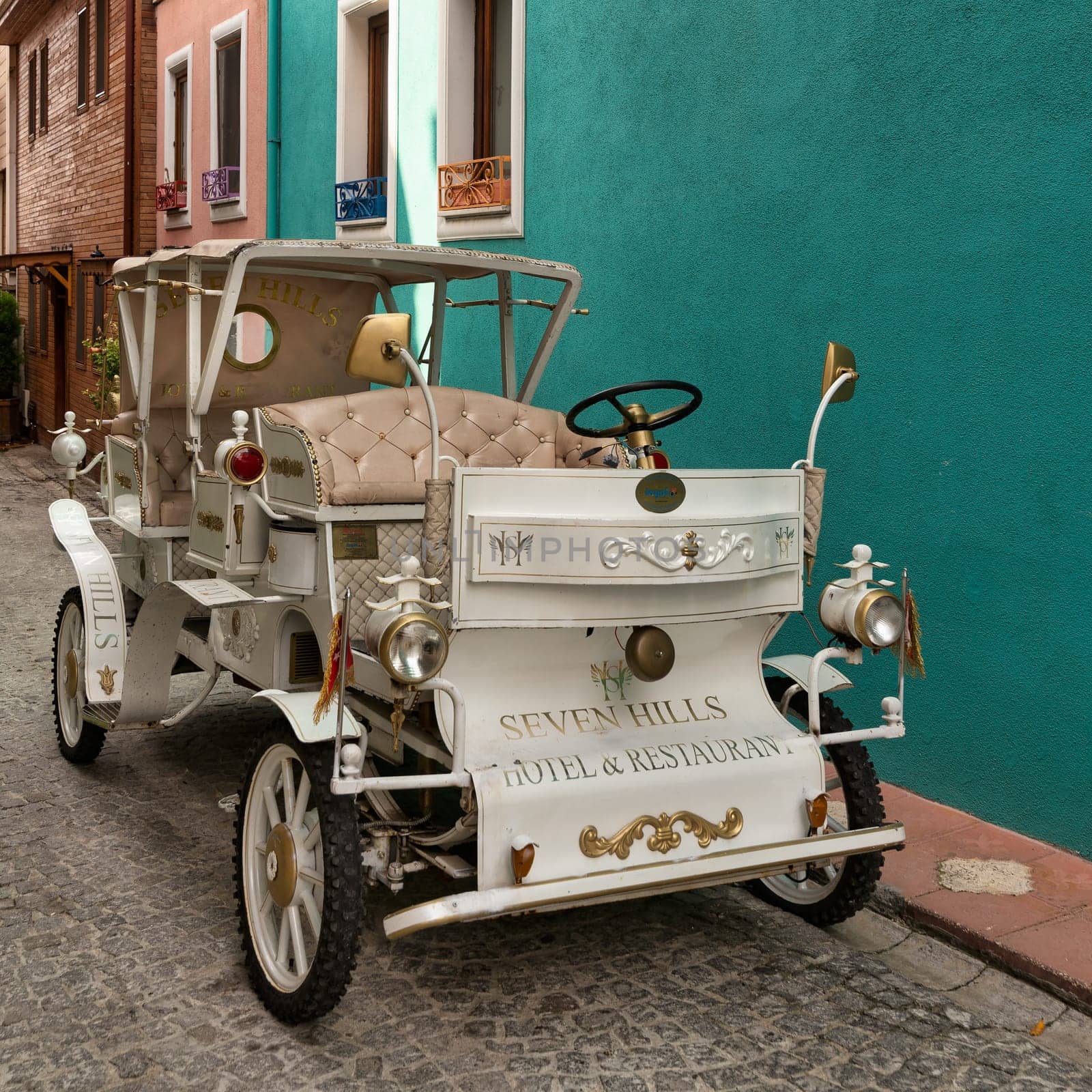 White antique car in a cobblestone alley over green wall of Seven Hills hotel, near Sultanahmet square, Fatih district, Istanbul, Turkey