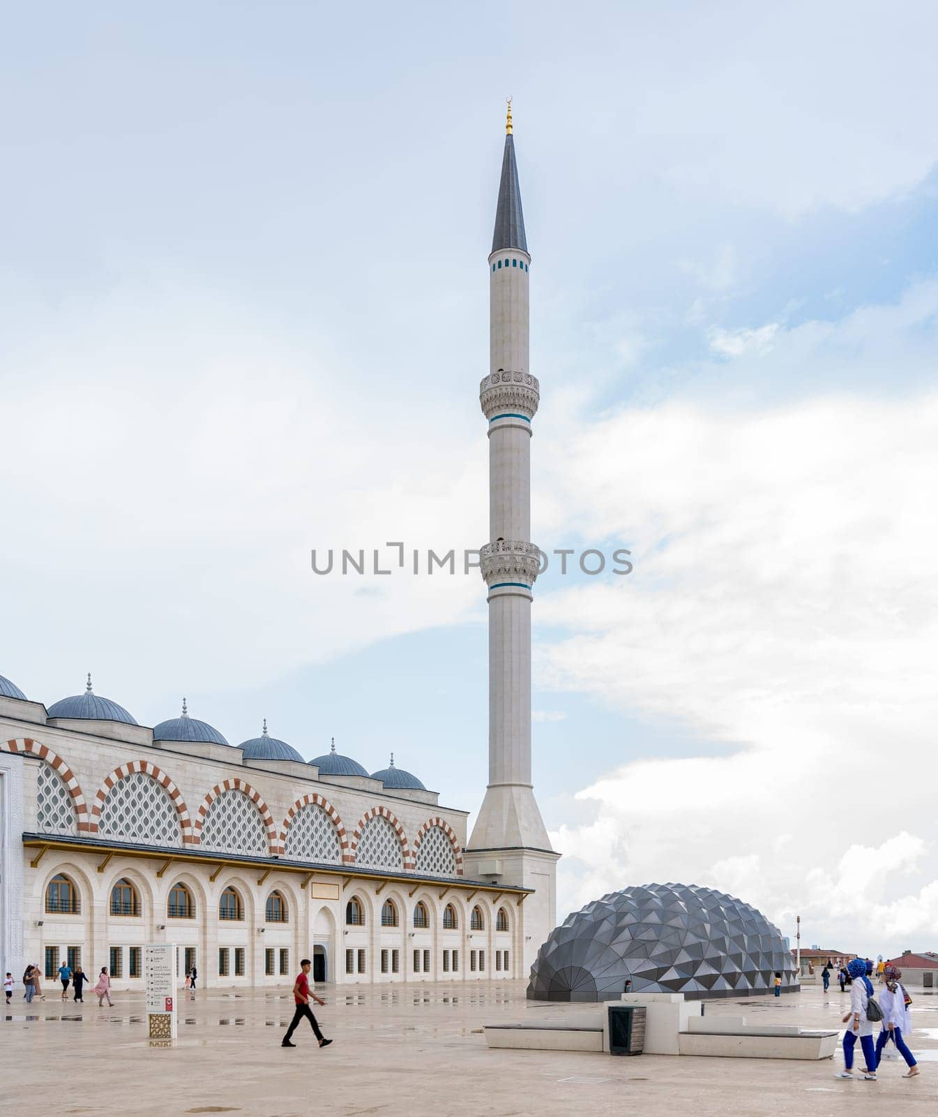Istanbul, Turkey - August 31 2022: Minaret of Grand Camlia Mosque, or Buyuk Camlica Camii, with few pedestrians, a modern complex for Islamic worship, built in 2019, located in Camlica hill, Uskudar
