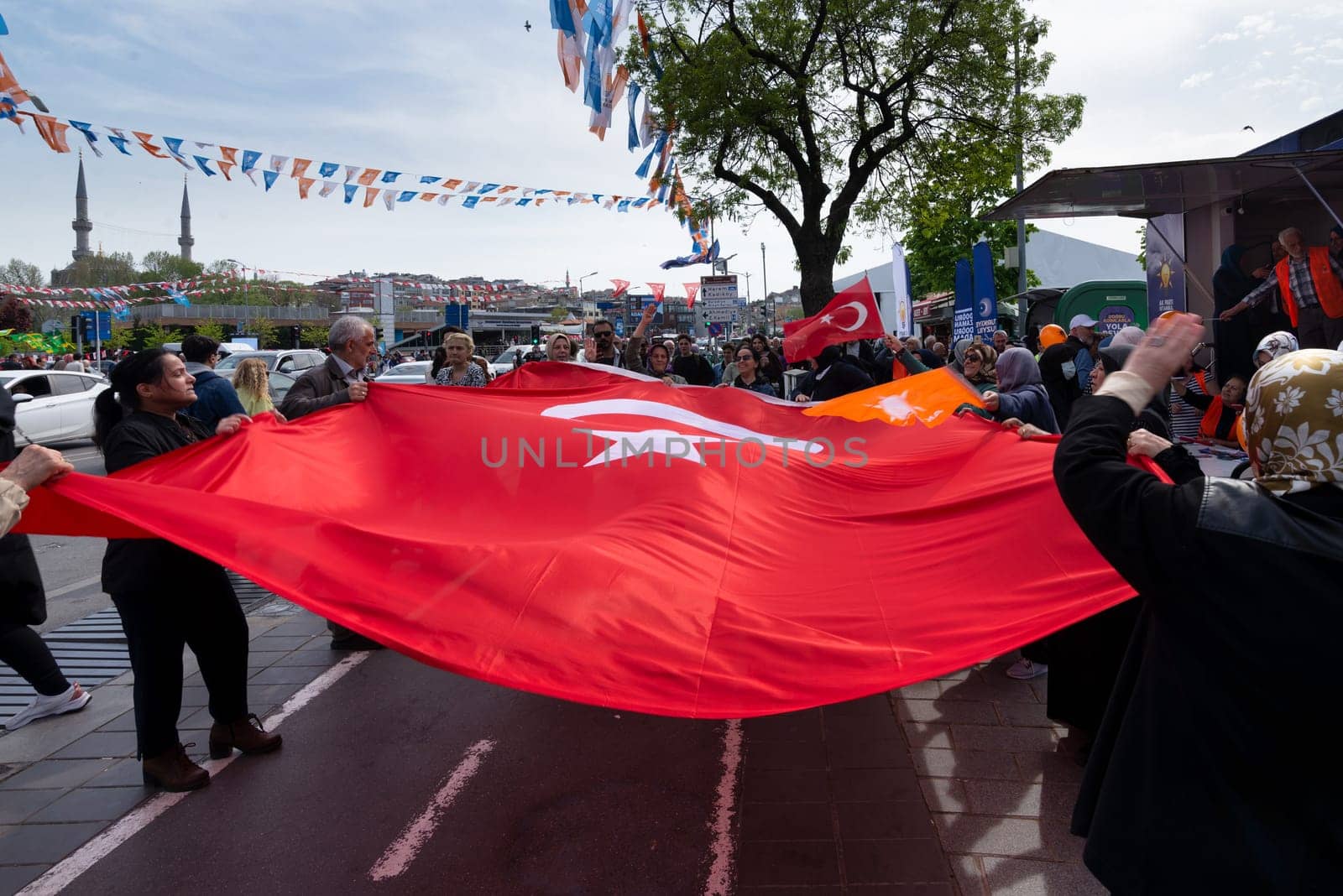 Istanbul, Turkey - May 3 2023: AK Party supporters waving a big Turkish flag in front of AK Party tent in the neighbourhood of Uskudar during 2023 elections
