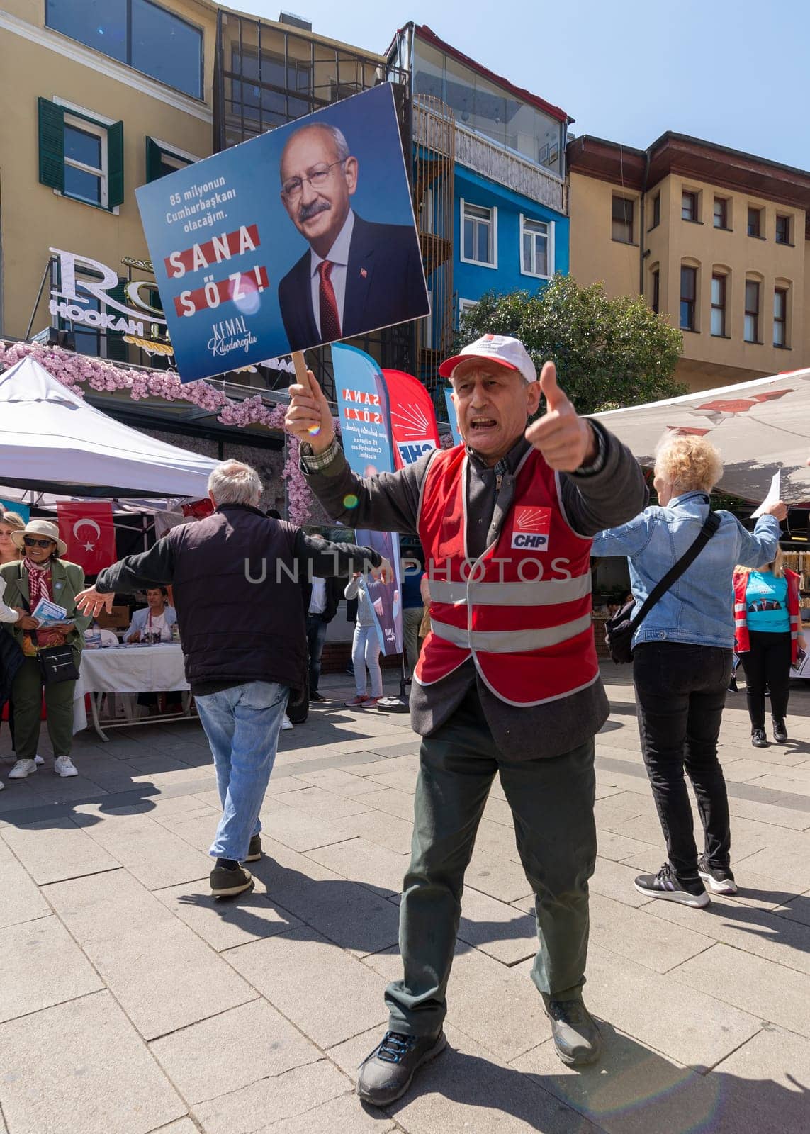 Istanbul, Turkey - May 13 2023: Man waving a big poster with Kemal Kilicdaroglu photo in front of Republican Peoples Party kiosk in the neighbourhood of Ortakoy during the 2023 elections