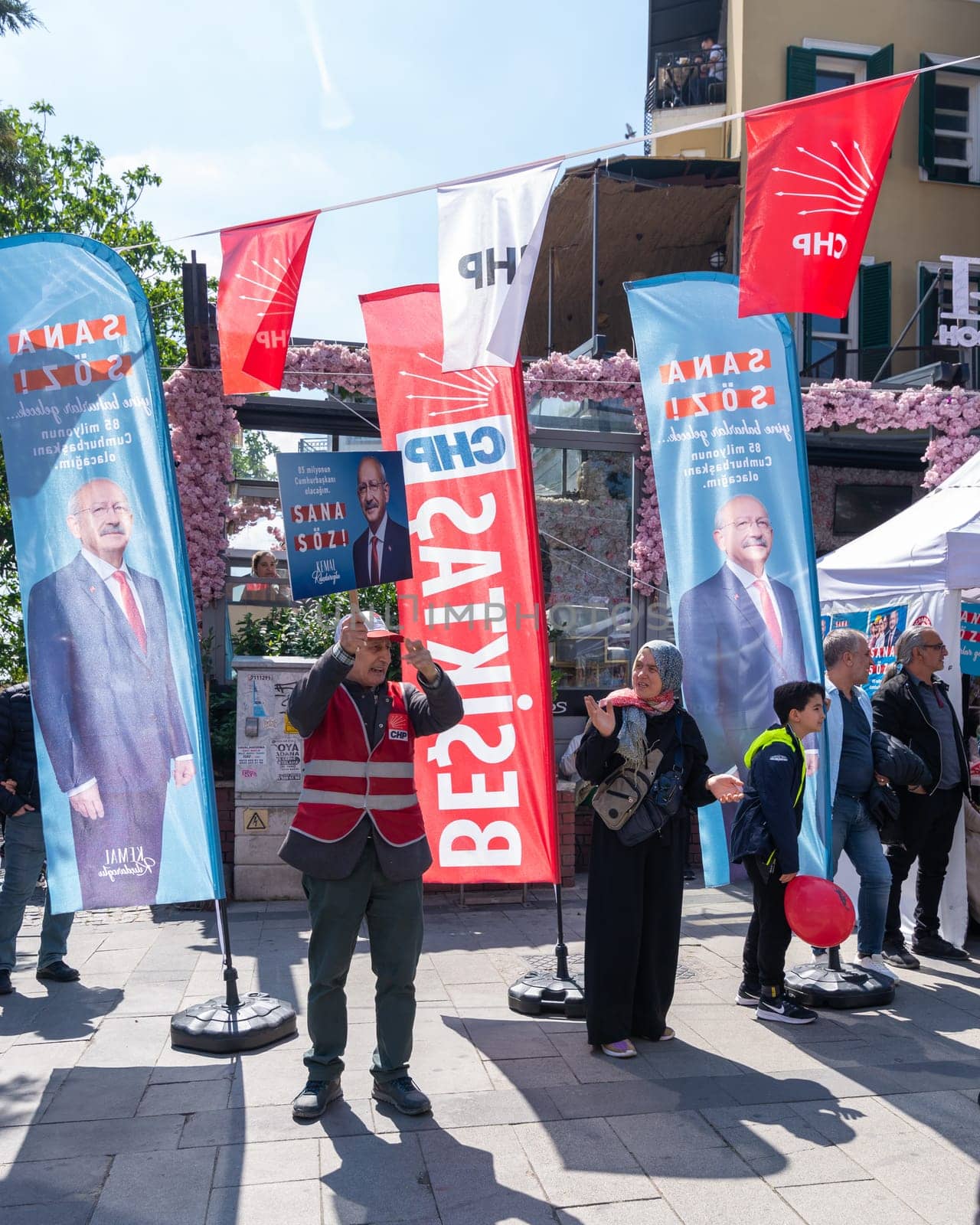 Istanbul, Turkey - May 13 2023: Man waving a big poster with Kemal Kilicdaroglu photo in front of Republican Peoples Party kiosk in the neighbourhood of Ortakoy during the 2023 elections