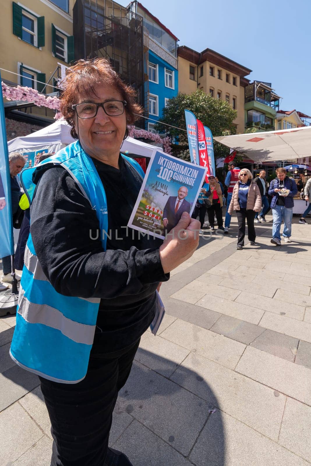 Istanbul, Turkey - May 13 2023: Woman holding election campaign brochure in front of Republican Peoples Party kiosk in the neighbourhood of Ortakoy during the 2023 elections