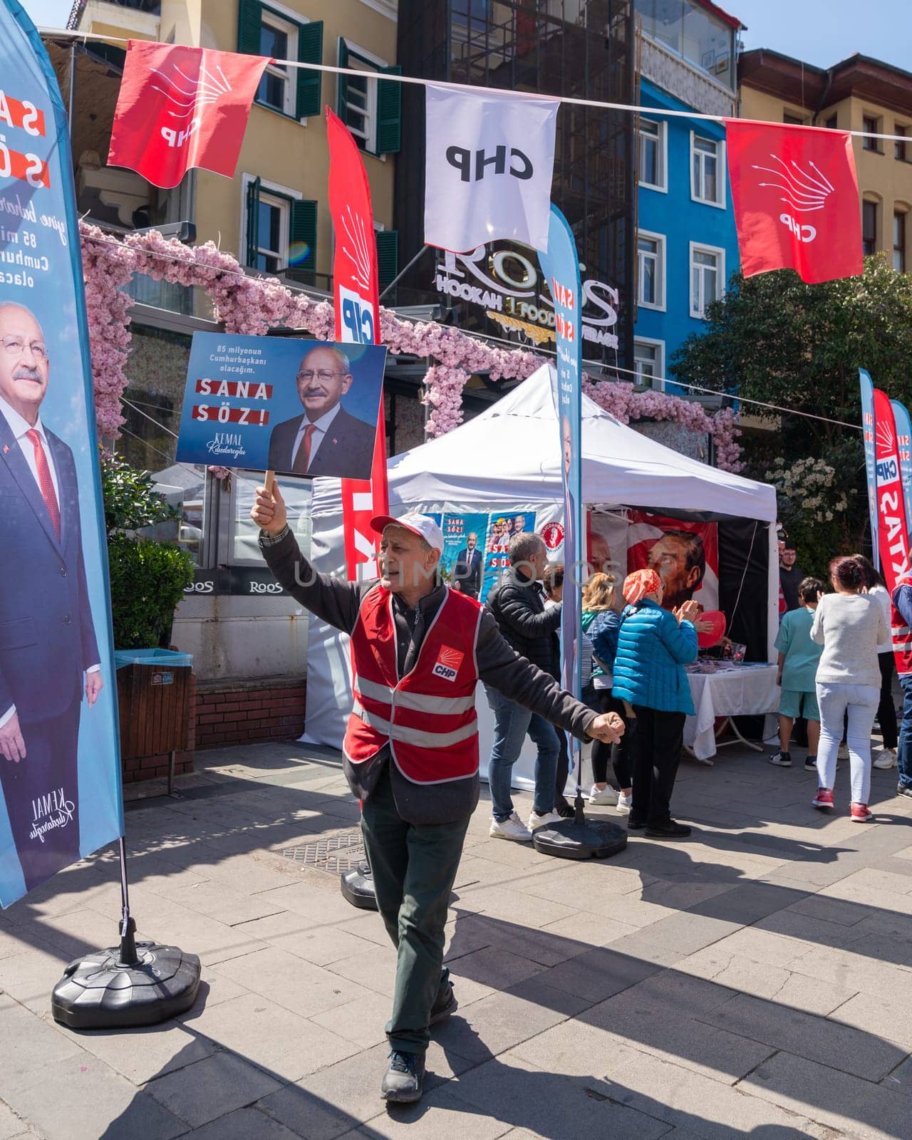Istanbul, Turkey - May 13 2023: Man waving a big poster with Kemal Kilicdaroglu photo in front of Republican Peoples Party kiosk in the neighbourhood of Ortakoy during the 2023 elections
