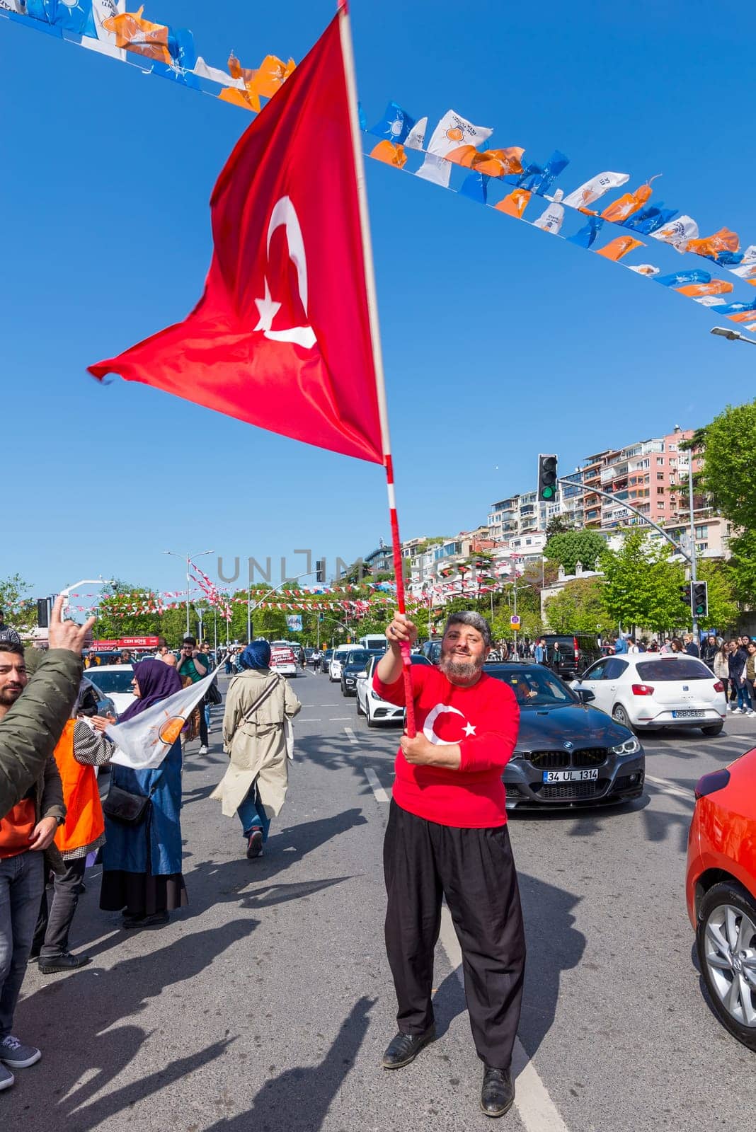 Istanbul, Turkey - May 13 2023: Supporter of AK Party waving a big Turkish flag in the street at the neighbourhood of Uskudar during 2023 elections