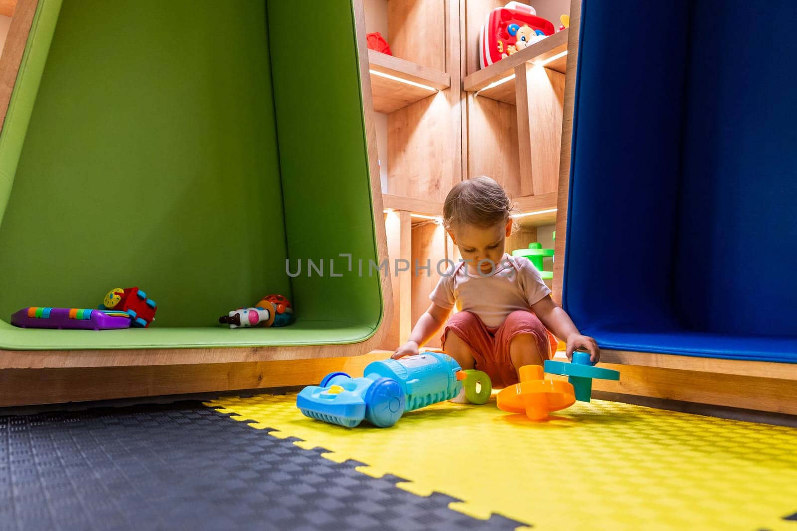 Little child enjoying playtime with colorful toys in a modern and interactive indoor playroom