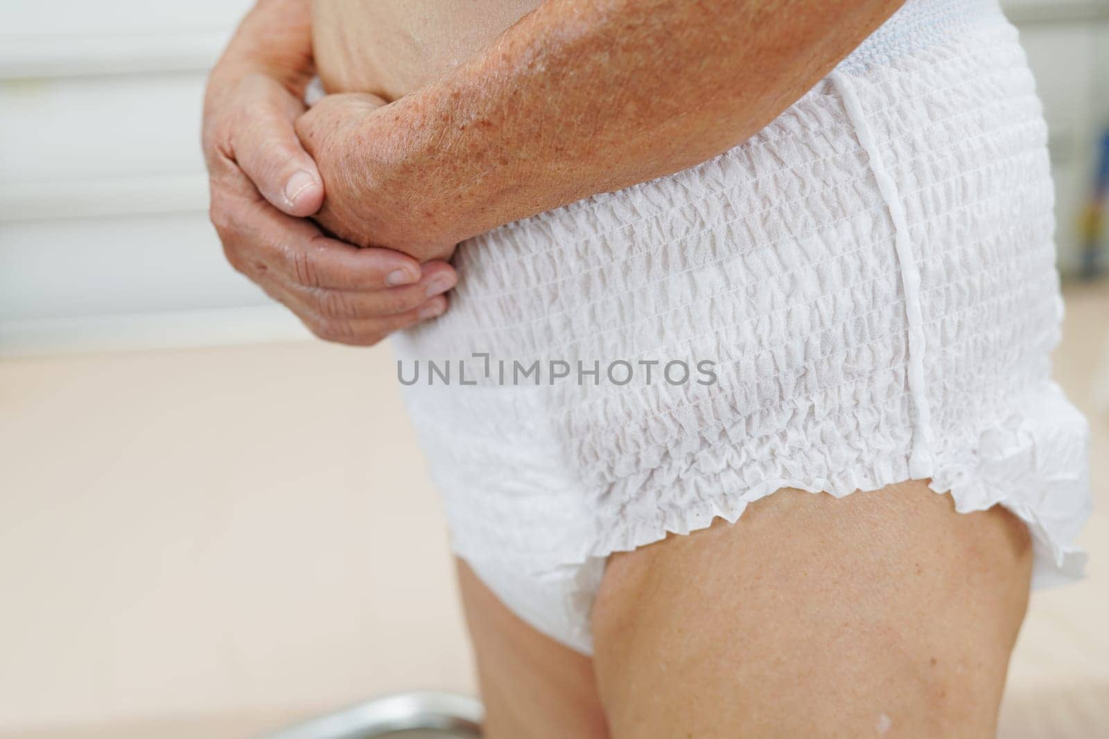 Asian elder senior woman patient wearing adult incontinence diaper pad in hospital.