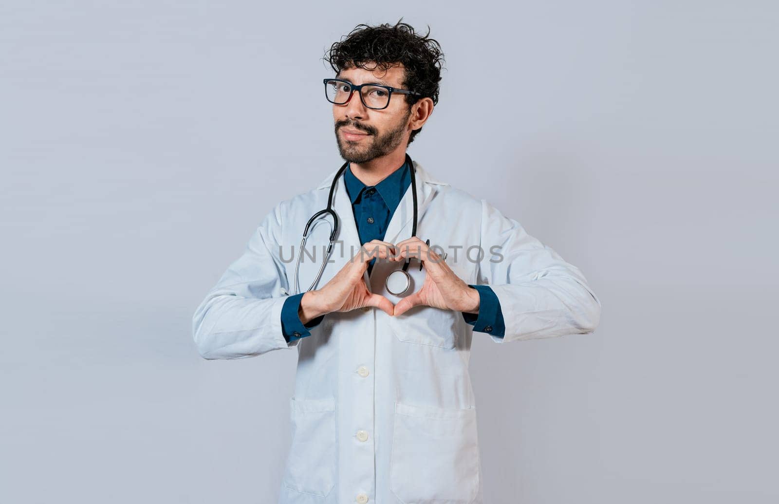 Handsome doctor making heart gesture with hands. Happy doctor pointing fingers down, Young doctor making heart shape isolated