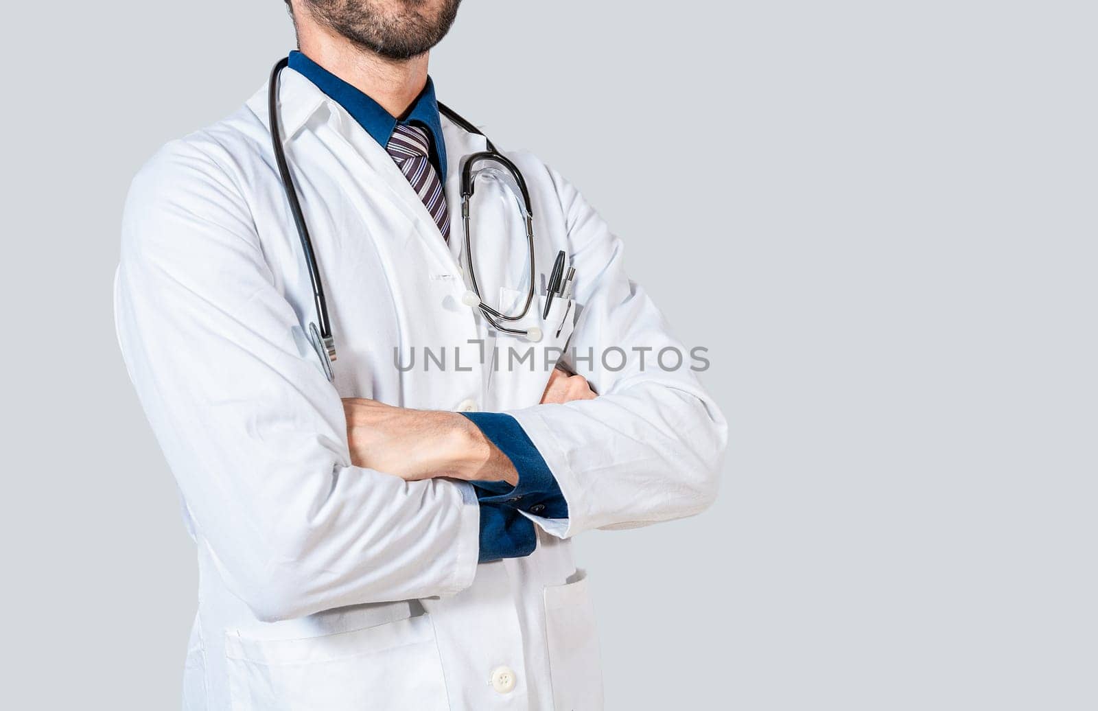 Young doctor with crossed arms isolated. Unrecognizable doctor with crossed arms on isolated background