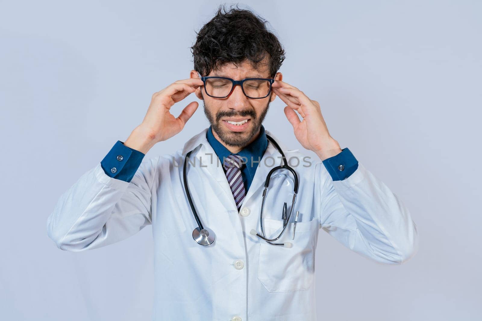 Young Doctor suffering with headache isolated. Doctor with migraine holding his head, Fatigued doctor with headache isolated