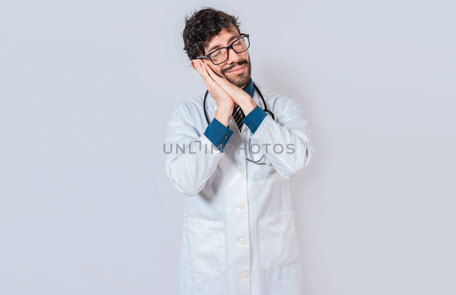 Doctor making sleep gesture isolated. Handsome doctor making sleep gesture with palms on his cheeks