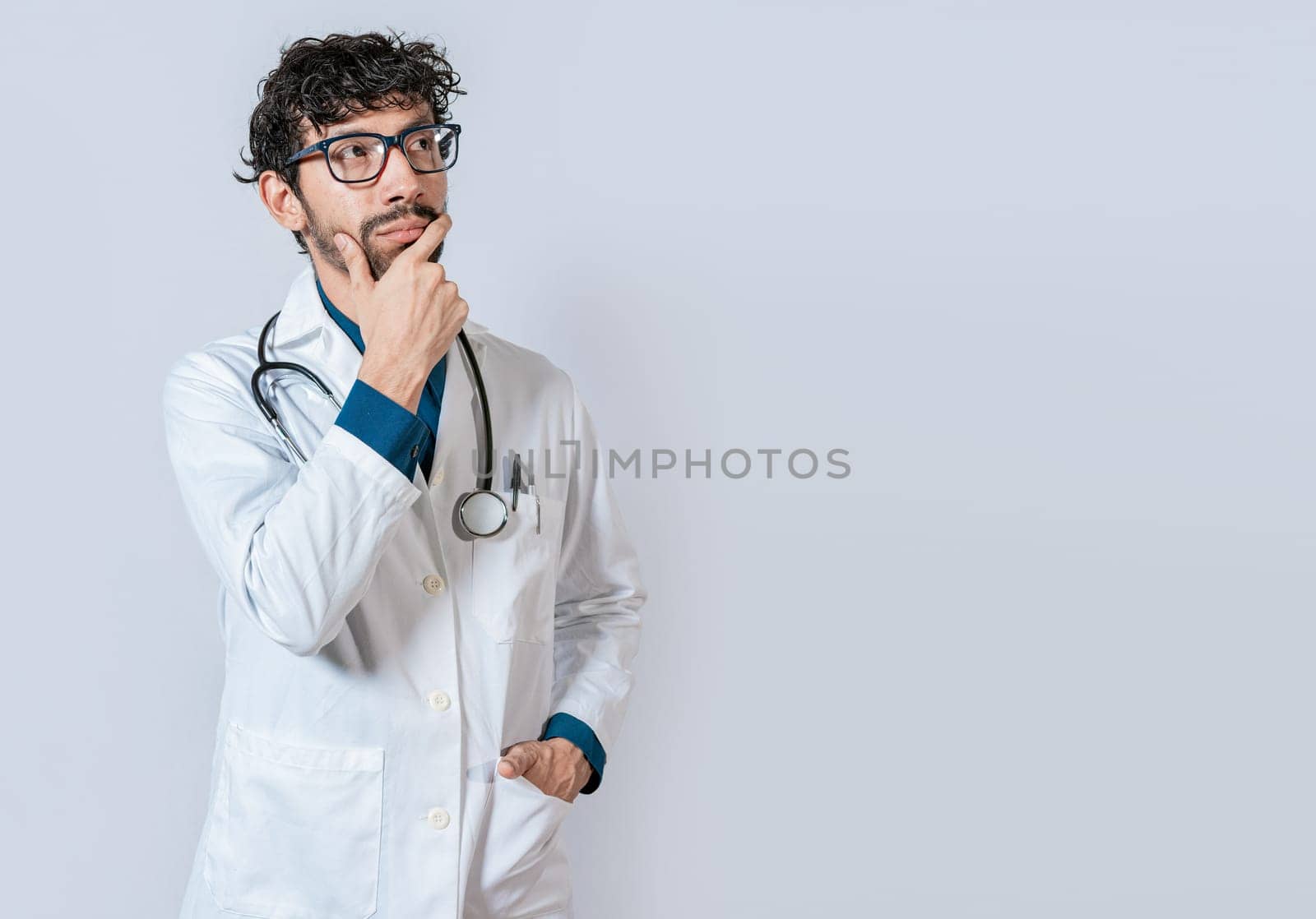 Doctor thinking with hand on chin. Young doctor thinking and looking up isolated, Pensive doctor man looking up isolated
