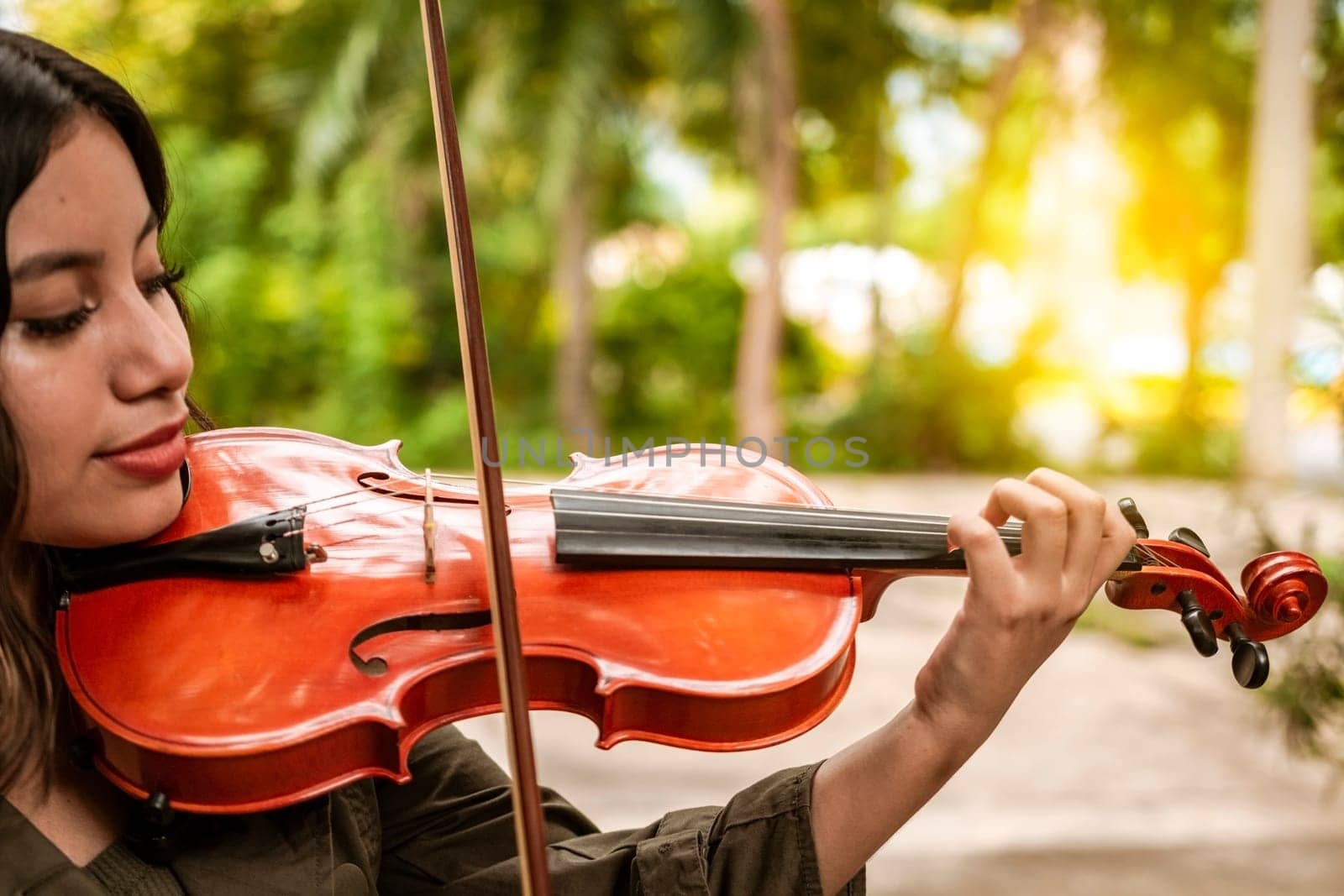Close up of a girl with her violin playing a melody outdoors, Concept of smiling female violinist. Attractive girl playing the violin outdoors. Portrait of a girl playing the violin outdoors