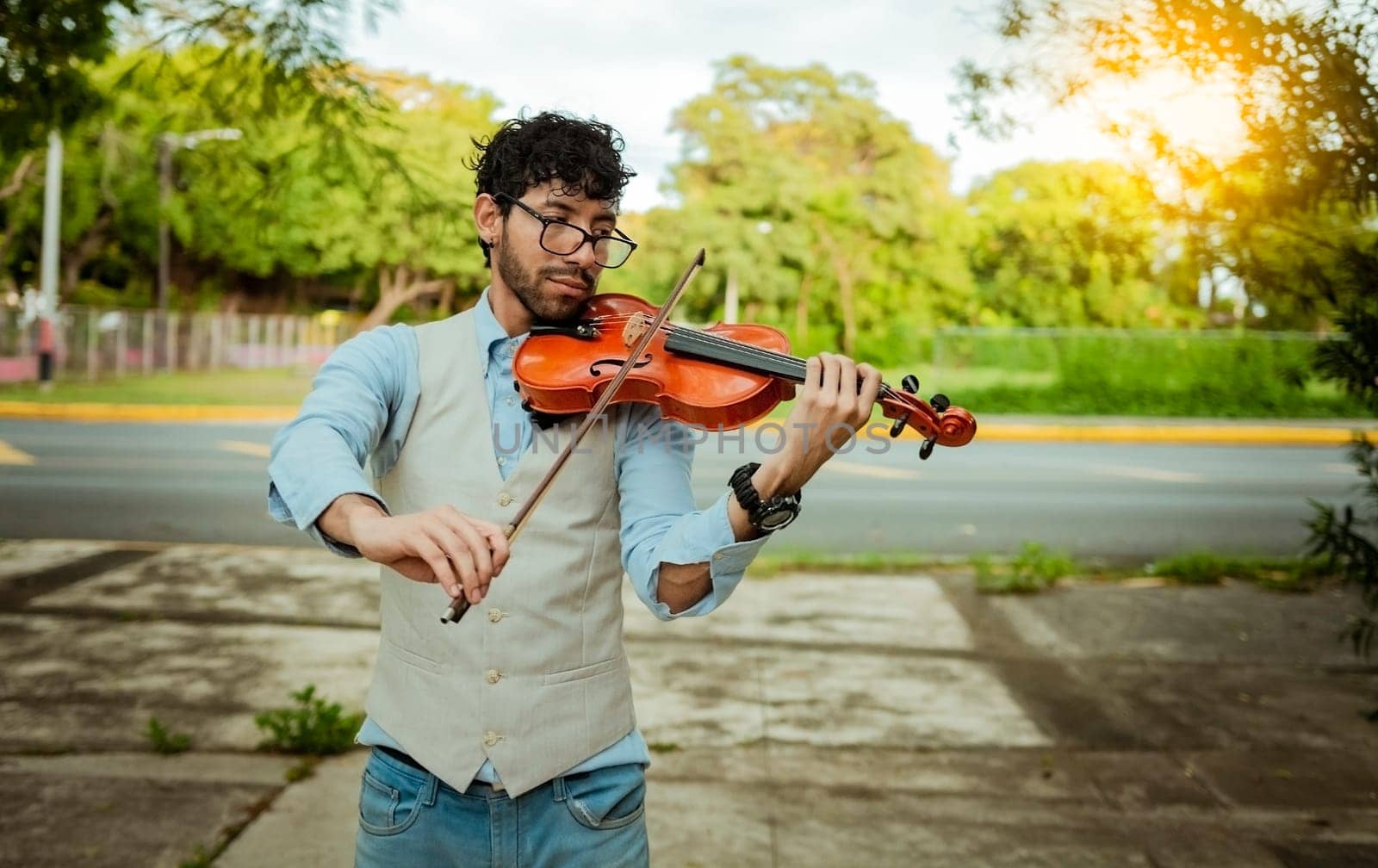 Violinist artist playing a melody outdoors, Portrait of man playing violin outdoor. Close up of violinist man playing in the street. Image of a person playing the violin outdoors