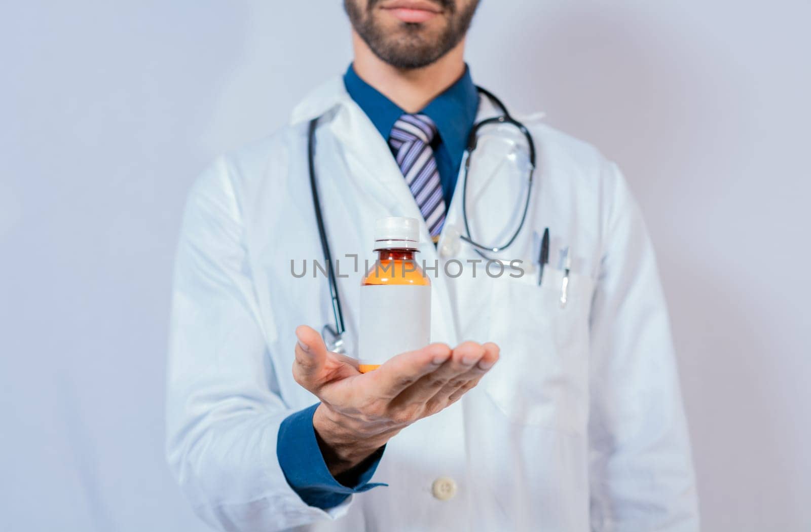 Doctor's hand holding a bottle of syrup. Doctor showing a bottle of syrup.