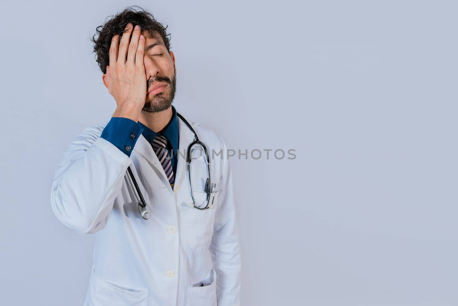 Exhausted doctor with hand on his forehead. Overworked doctor with hand on forehead isolated