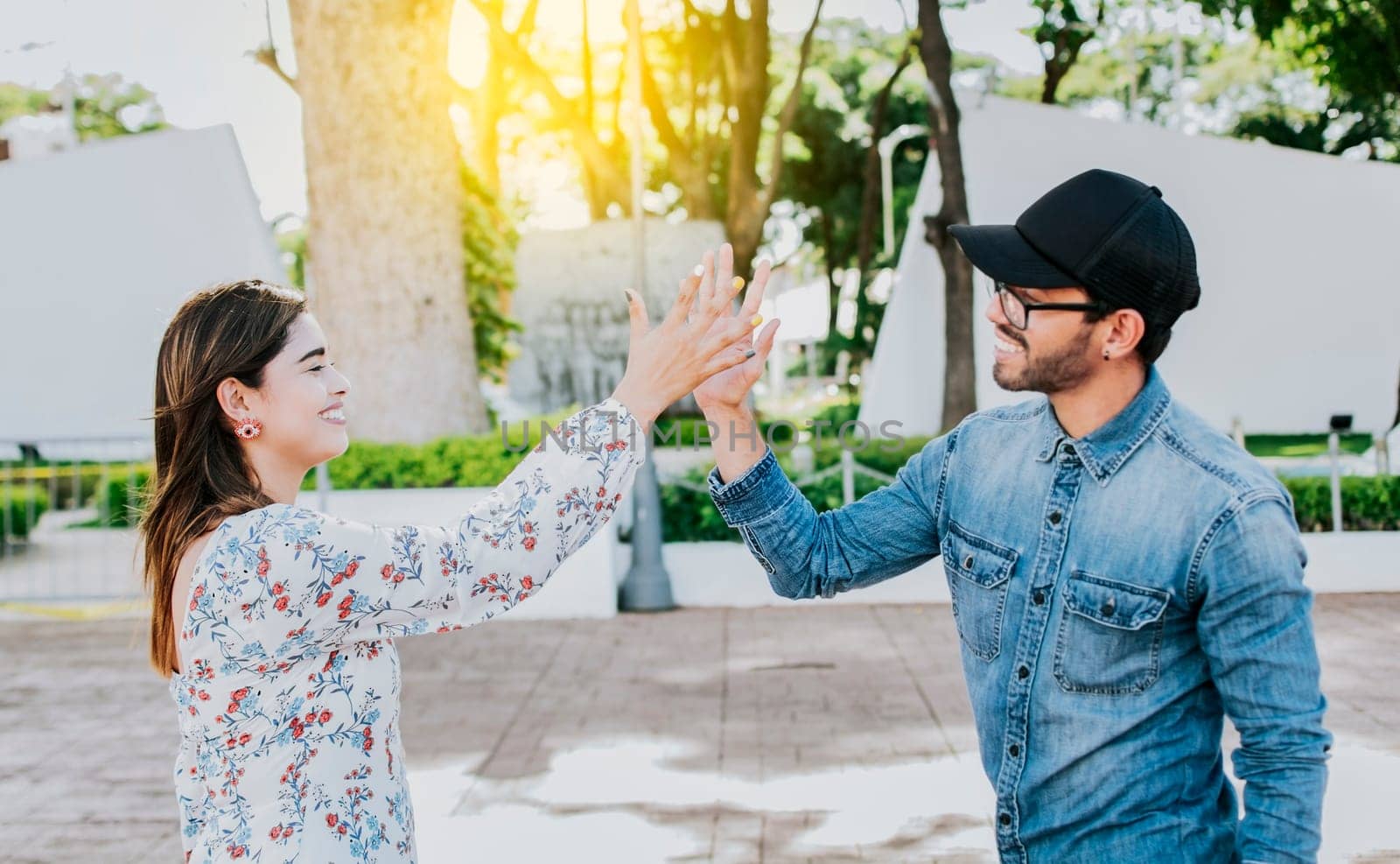 A girl and a guy shaking hands on the street. Two young smiling teenagers shaking hands in the street. Concept of man and woman shaking hands on the street.
