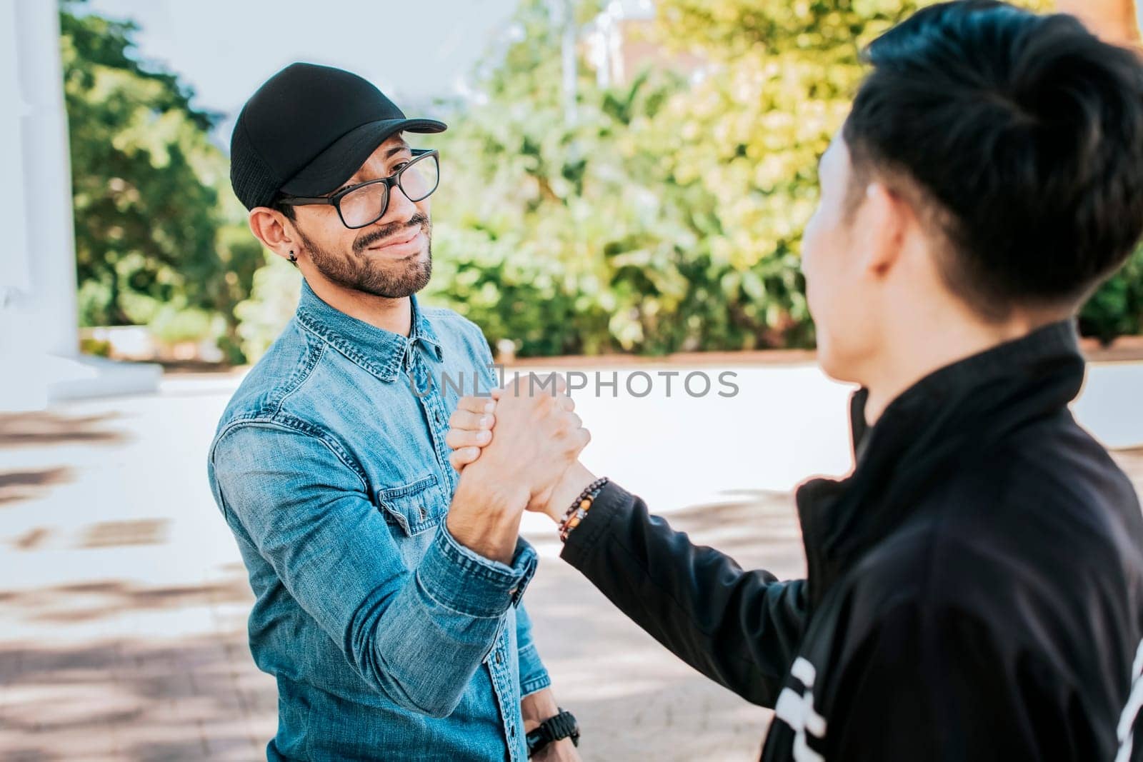 Two happy friends shaking hands in the street. Two people shaking hands on the street. Two smiling friends greet each other on the street