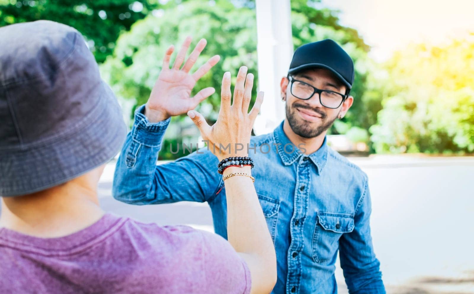 Back view of two smiling friends shaking hands on the street. Two smiling friends shaking hands in a park. Concept of two friends greeting each other with a handshake on the street