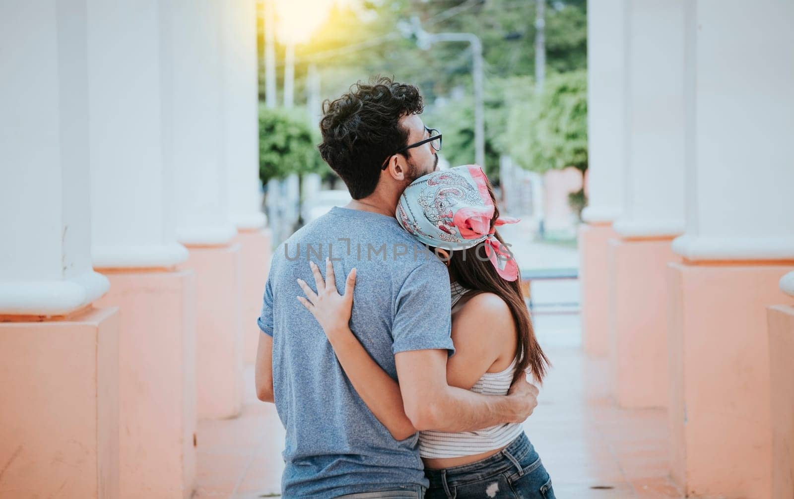 Back view of young woman hugging her boyfriend. Back view of girl hugging her boyfriend outdoors, Back view of happy couple hugging outdoors