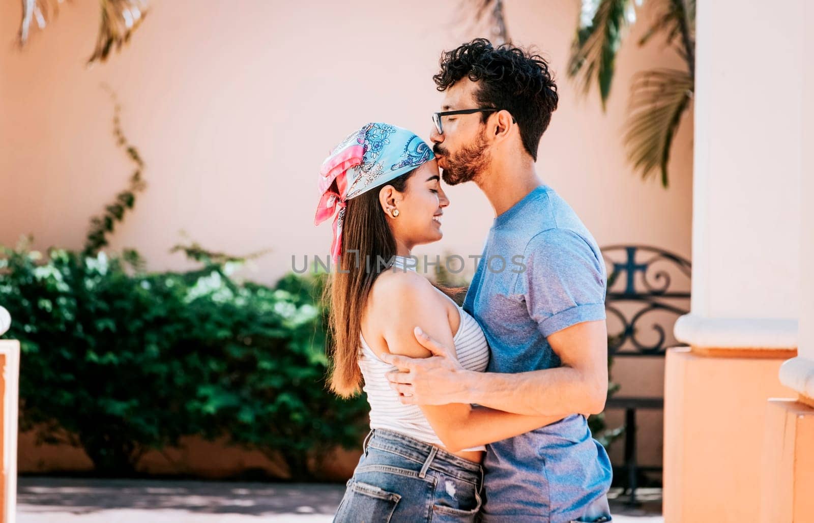 Cute couple embracing the boyfriend kisses the girl forehead. Portrait of beautiful couple in love. Boyfriend tenderly kissing his girlfriend forehead. Man kissing his girlfriend forehead outside