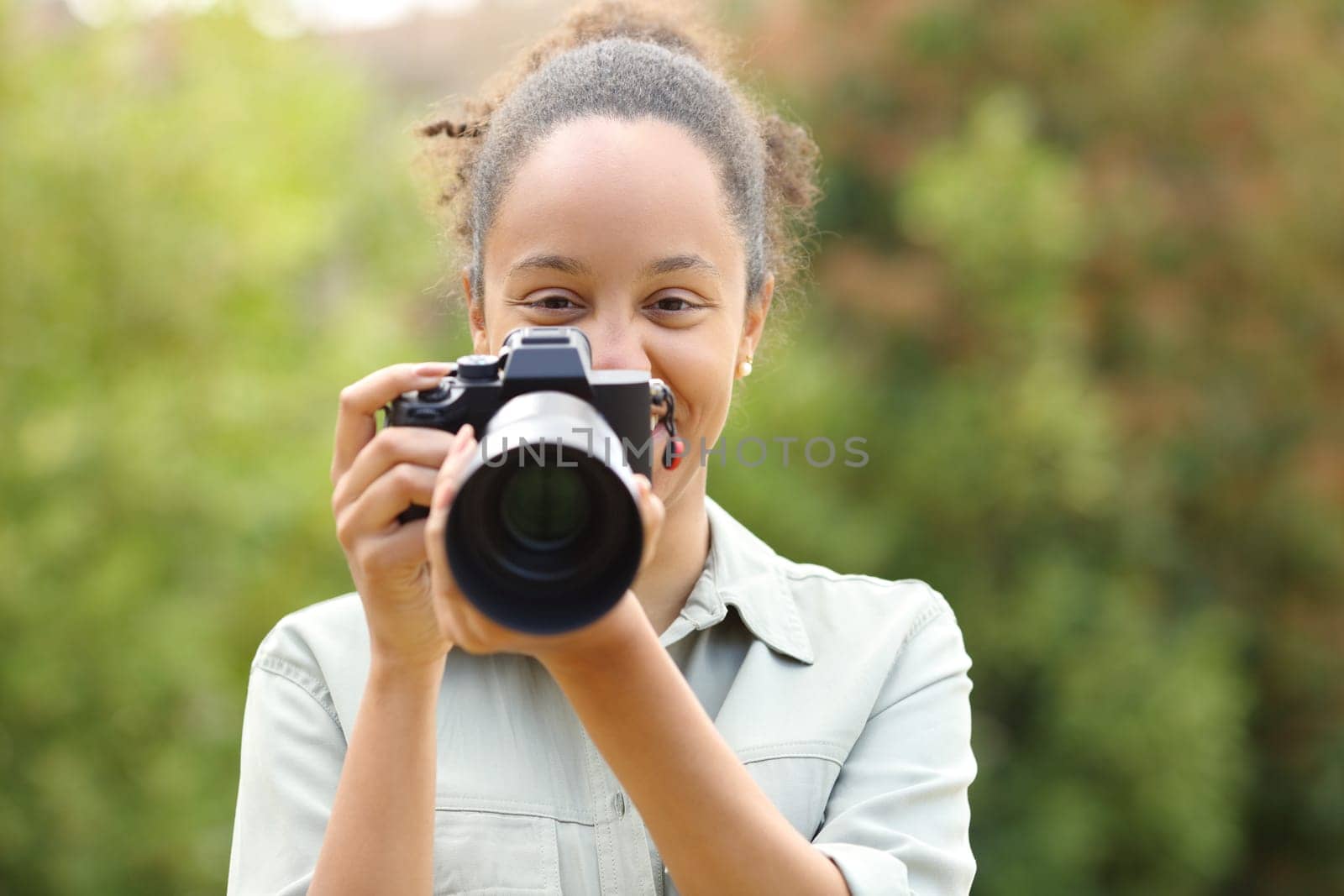 Front view portrait of a happy black photographer looking at camera