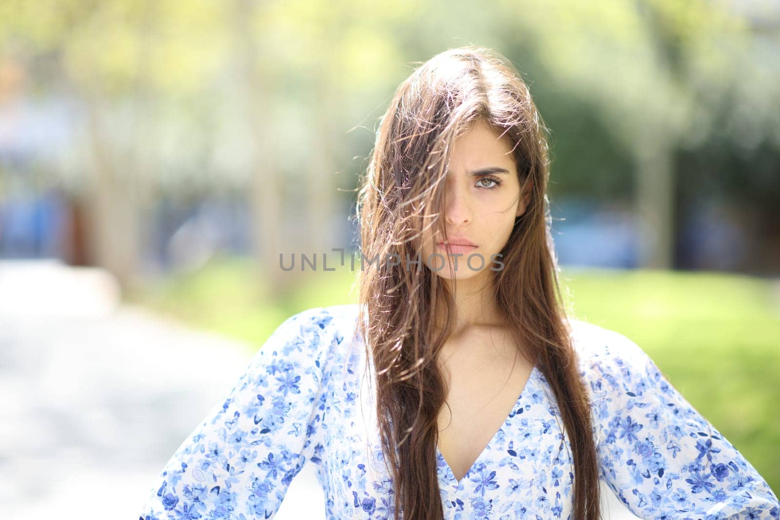 Angry woman with tousled hair a windy day looking at camera in the street