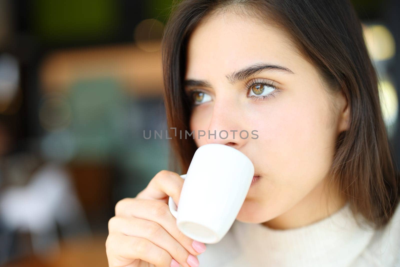 Portrait of a serious woman drinking coffee looking away in a bar