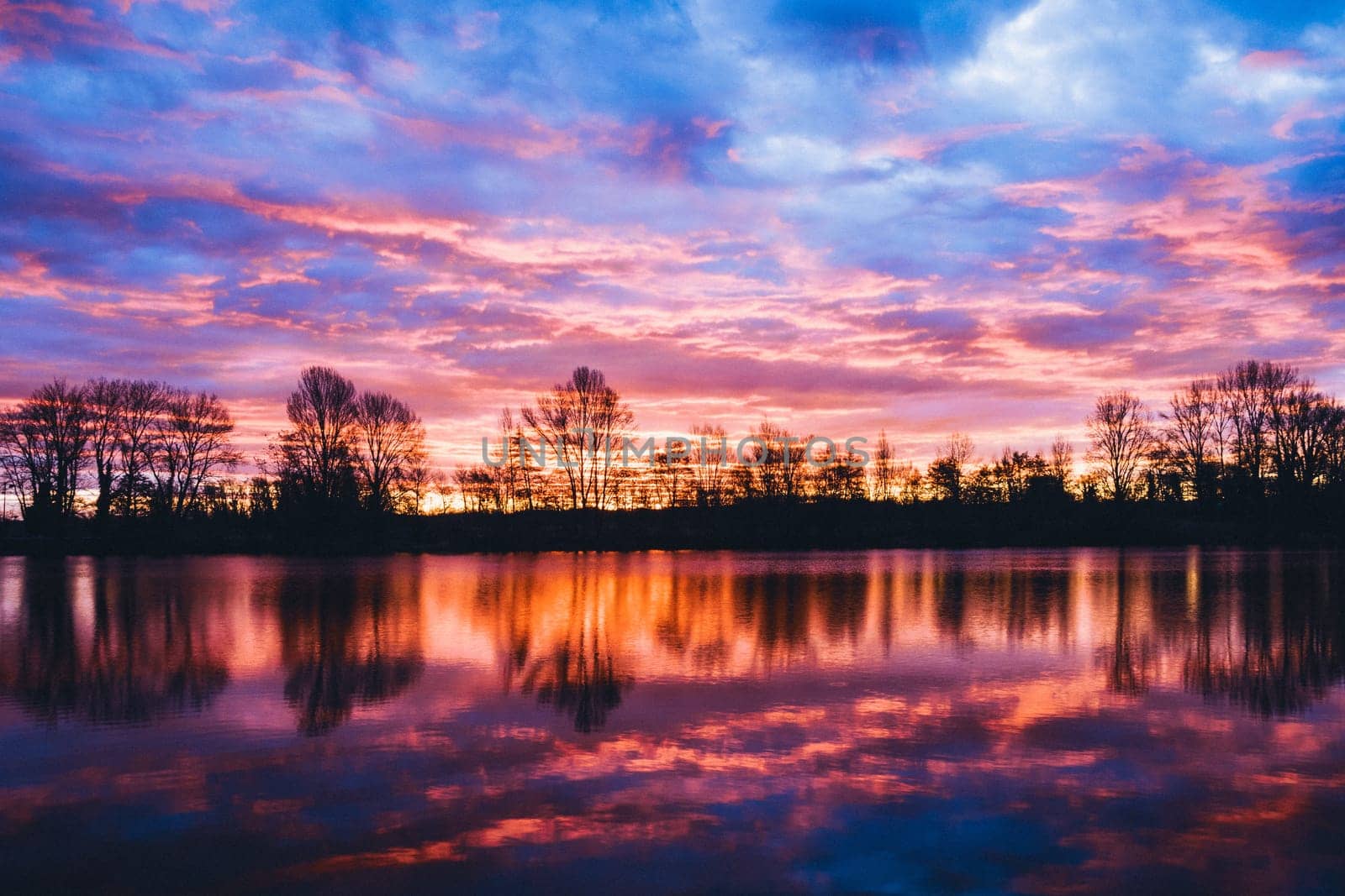 Nightscape photo at Adour French river in blazing red sunset with dramatic clouds floating. Real photography