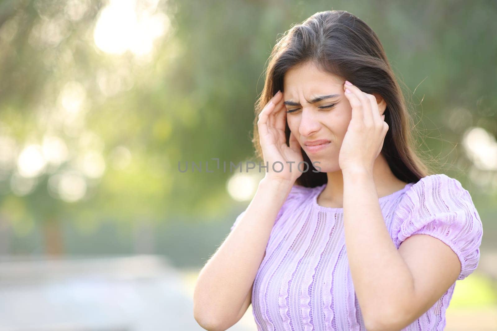 Woman suffering migraine walking in a park