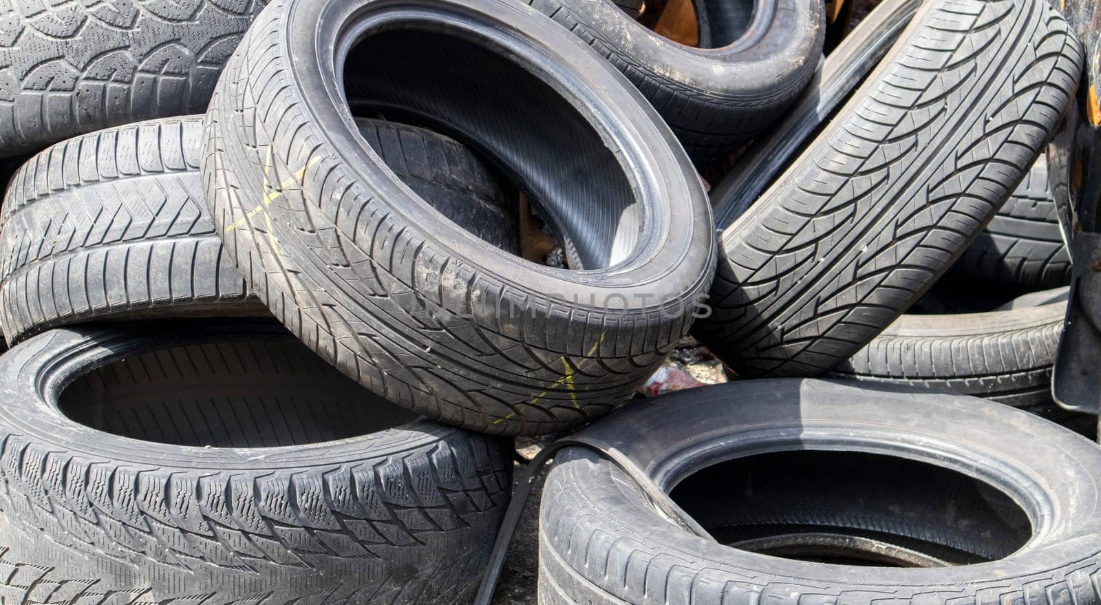 Industrial dump for the processing of used tires and rubber tires. Pile of old tires and wheels for rubber recycling. Tire dump. Recycling of used tires. Produced reclaimed tire rubber