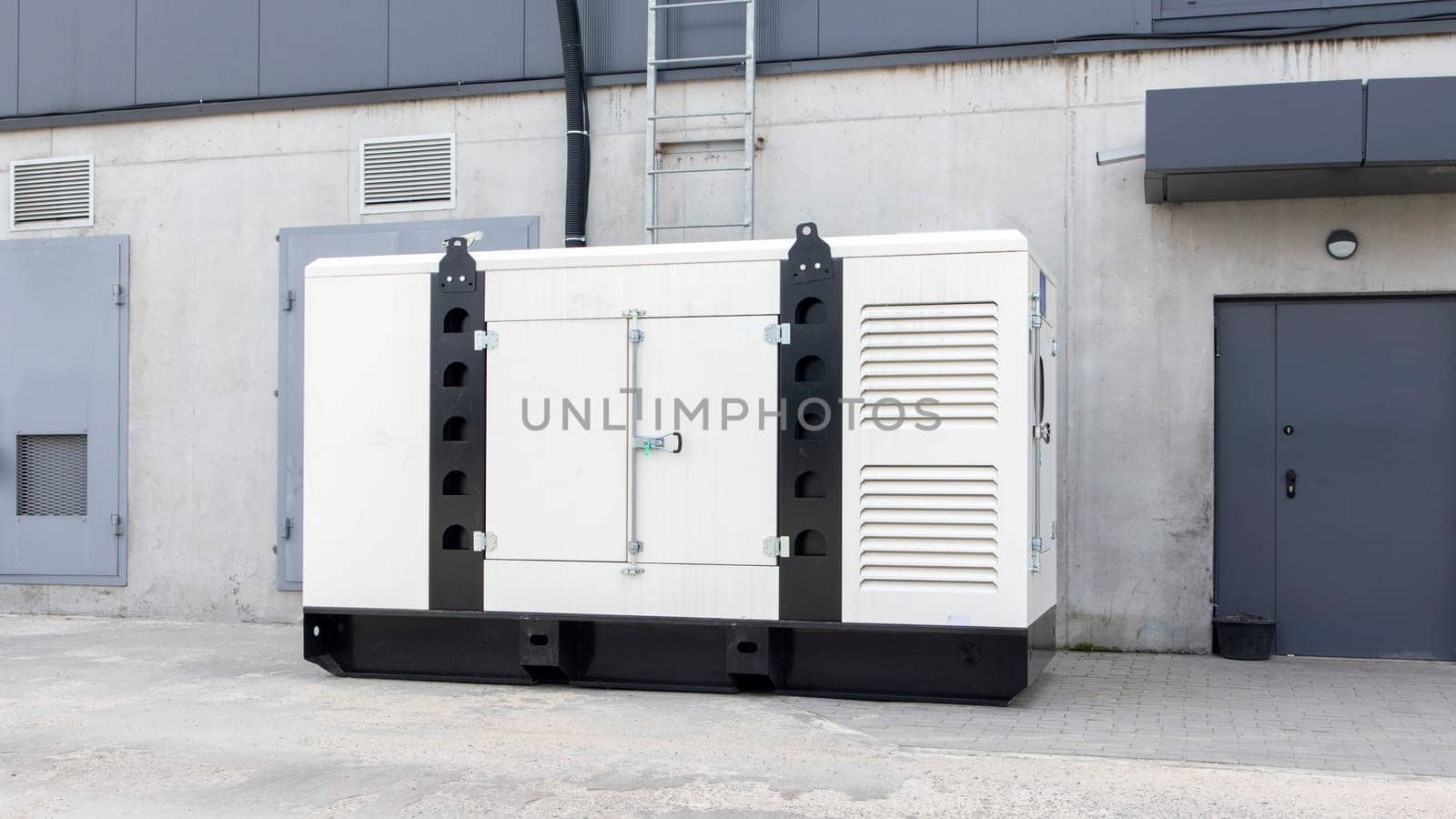 White auxiliary diesel generator for emergency power supply. Industrial generator connected to the control panel by a cable wire. Backup power supply of the generator
