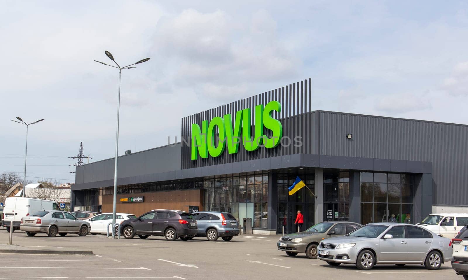 Ukrainian supermarket chain Novus. Green large signboard of the shopping center outside, on the street. Signboard against the sky. The building of the supermarket. Ukraine, Kyiv - May 01, 2023