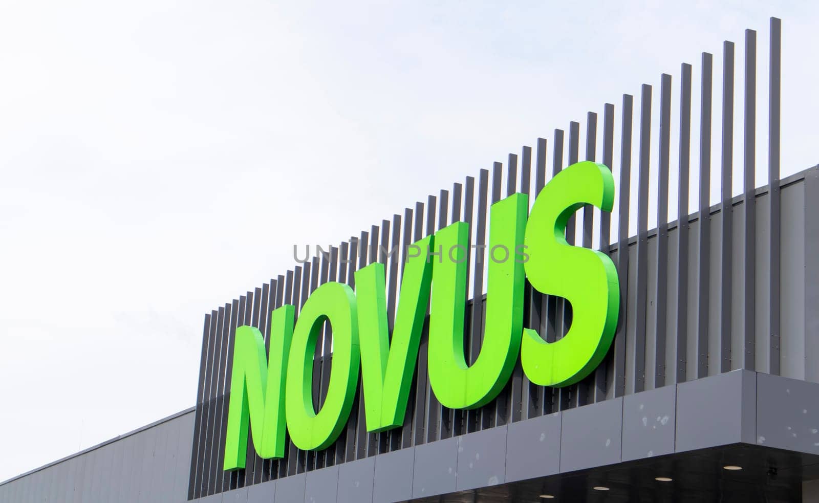 Ukrainian supermarket chain Novus. Green large signboard of the shopping center outside, on the street. Signboard against the sky. The building of the supermarket. Ukraine, Kyiv - May 01, 2023