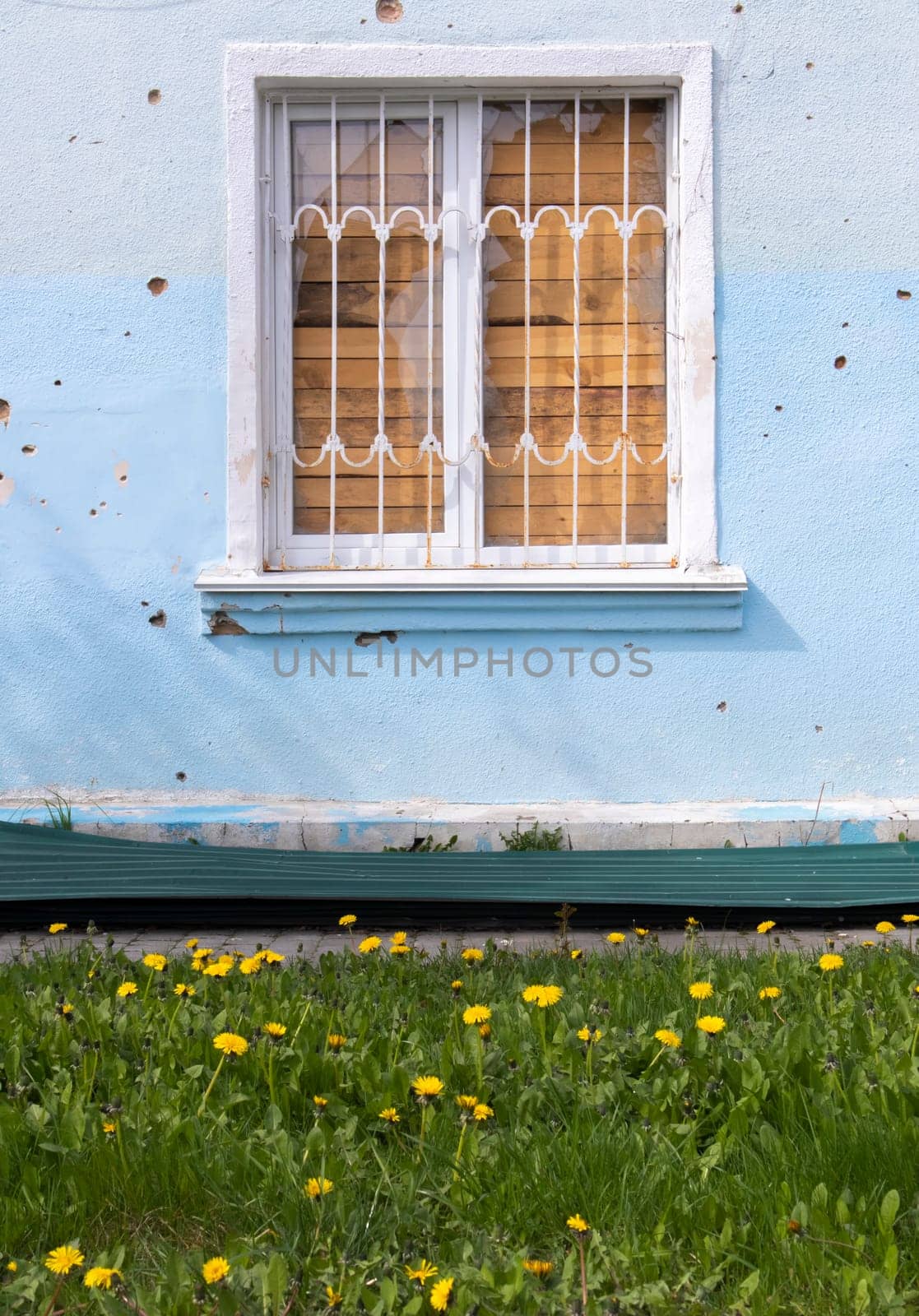 The buildings were hit by shelling. Boarded up windows and damaged facade. Preparing the house for hostilities and war. Destroyed houses in the city during the war in Ukraine