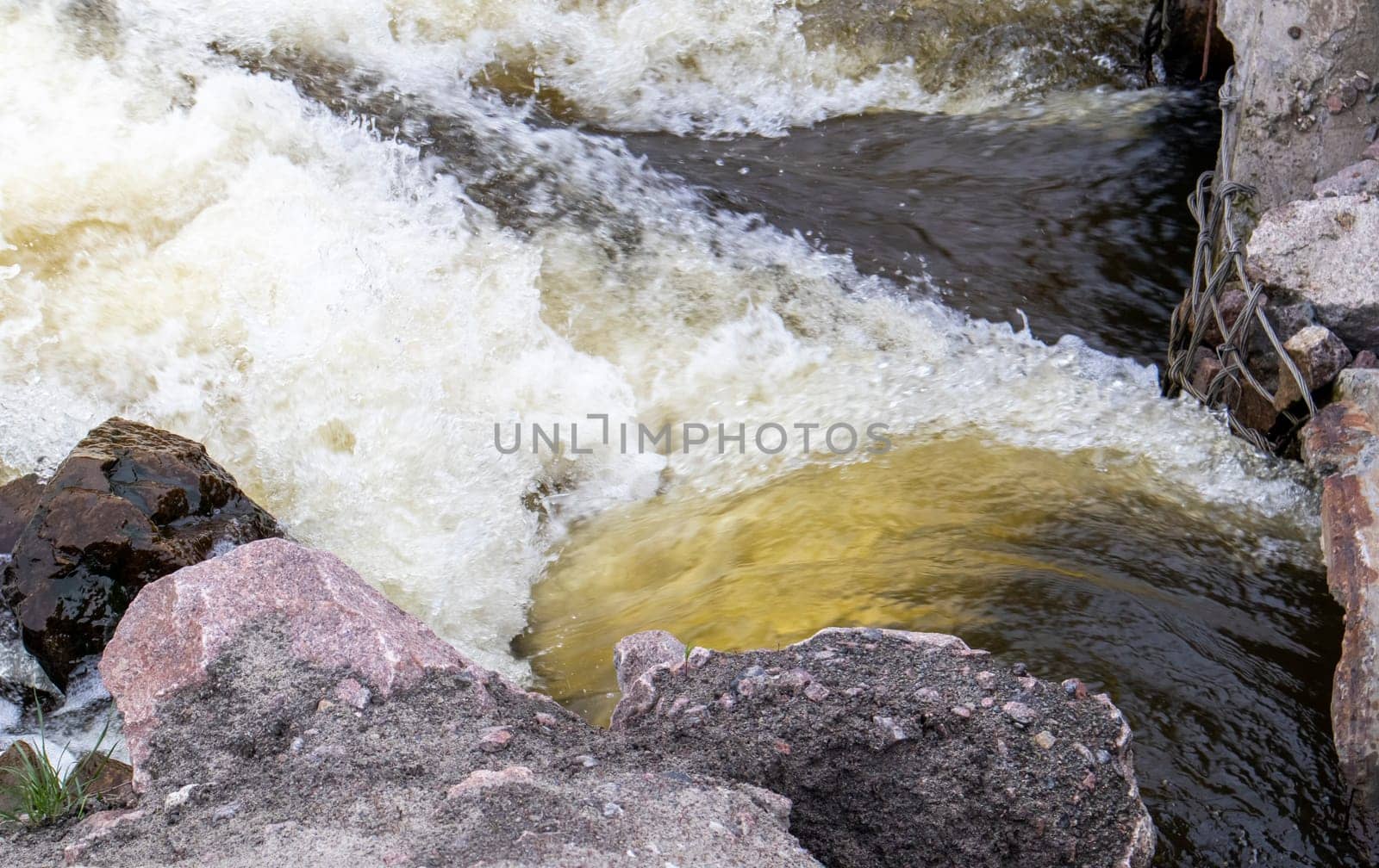 River rapids. Close up abstract background of falling water. Water flows over river rocks. A beautiful powerful stream of a stormy mountain river. The river rushes with fast-flowing water