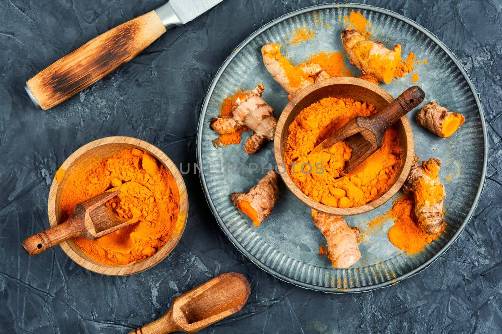 Raw turmeric root and turmeric or curcuma powder on a retro wooden background. Homeopathic herbs.