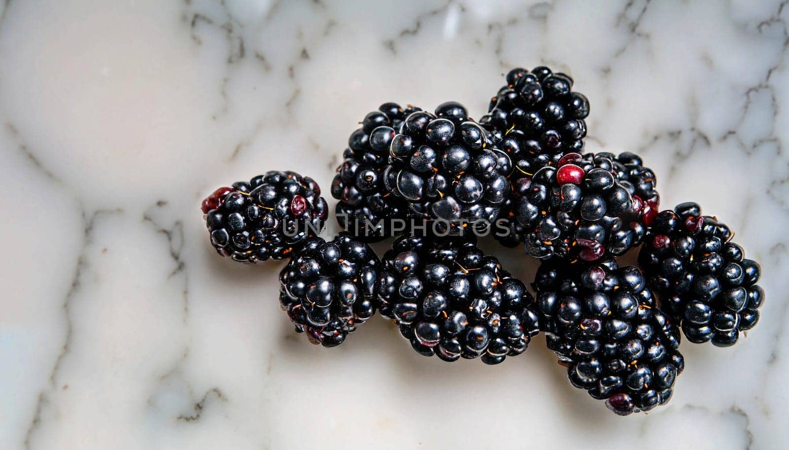 Overturned mug with blackberries on white marble table, closeup