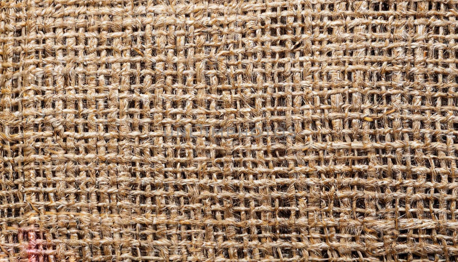 Natural textured background of intertwined threads. Macro photo of the texture of old burlap. Light brown abstract background.