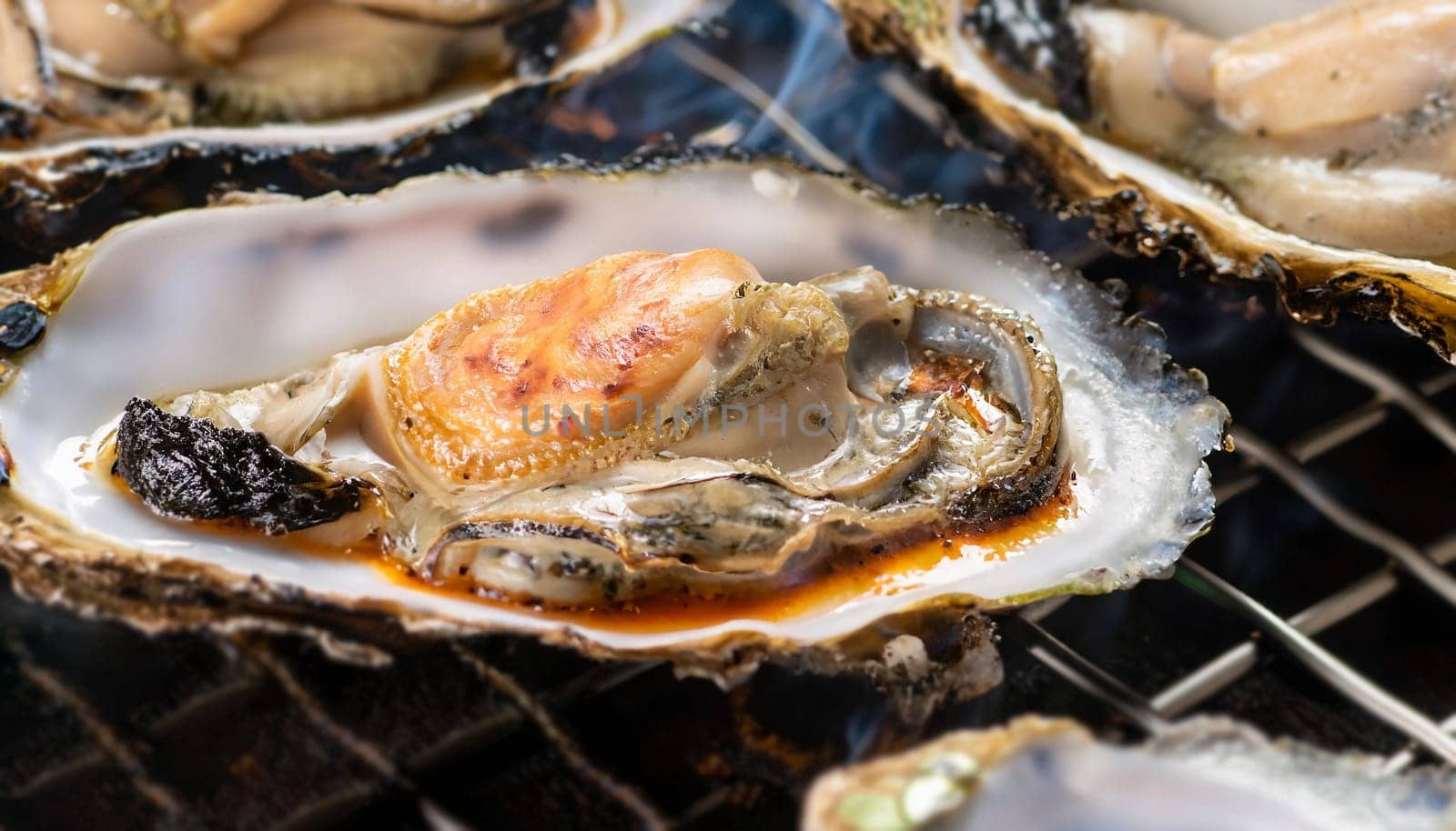 Grilling fresh hotate japanese scallops and kaki oysters in shells on barbeque grill with glowing coals, popular Otaru city street food, Japan