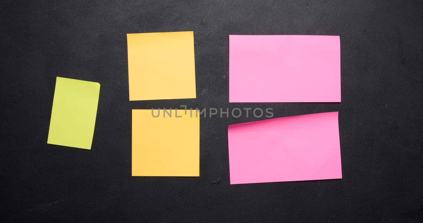 Multicolored paper stickers on a black chalkboard, space for notes and labels