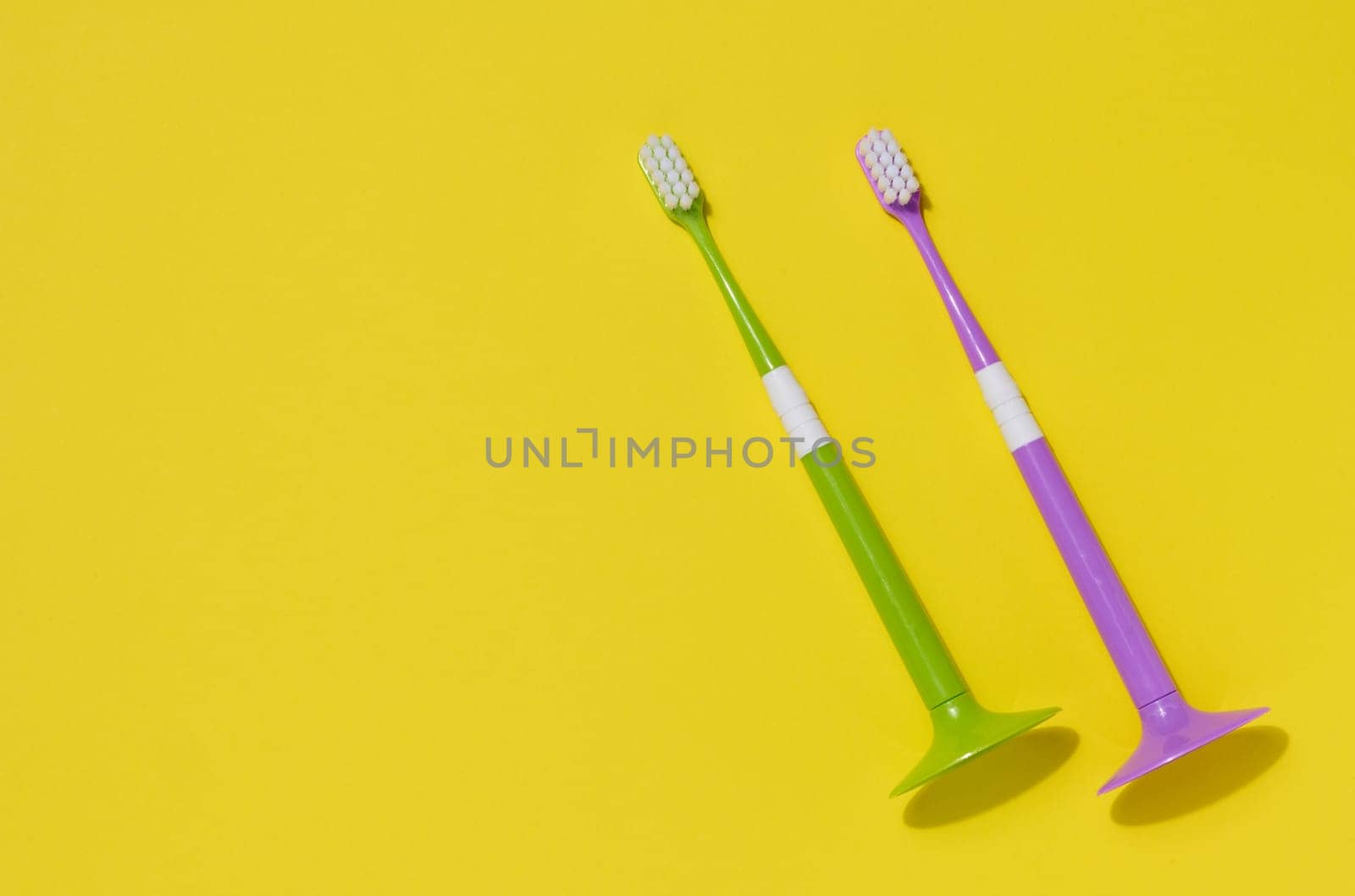 Two plastic toothbrushes on a yellow background, oral hygiene