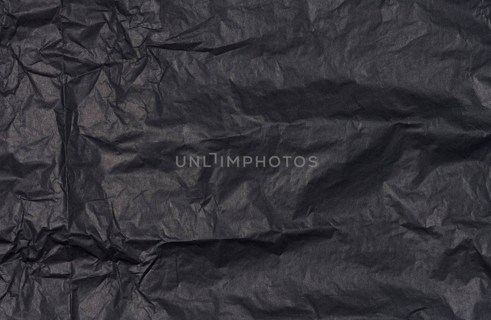 Crumpled sheet of black parchment paper, abstract background