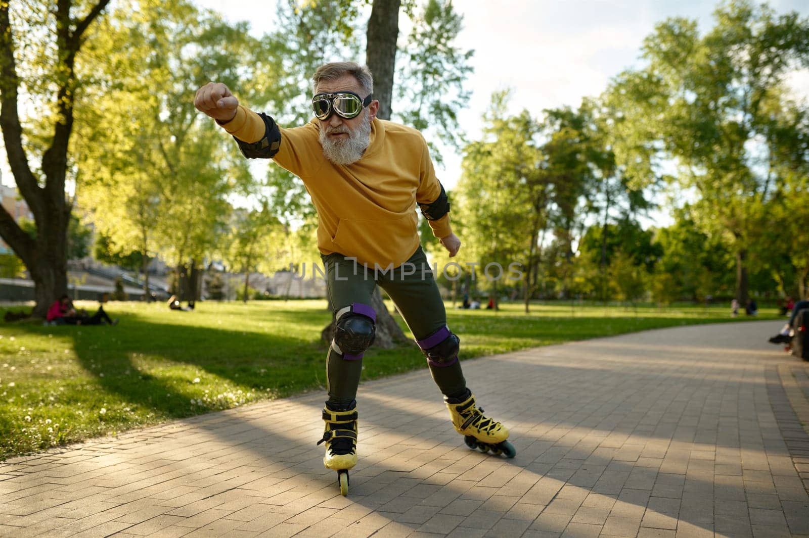 Funny mature man wearing goggles riding fast on roller skates in city street