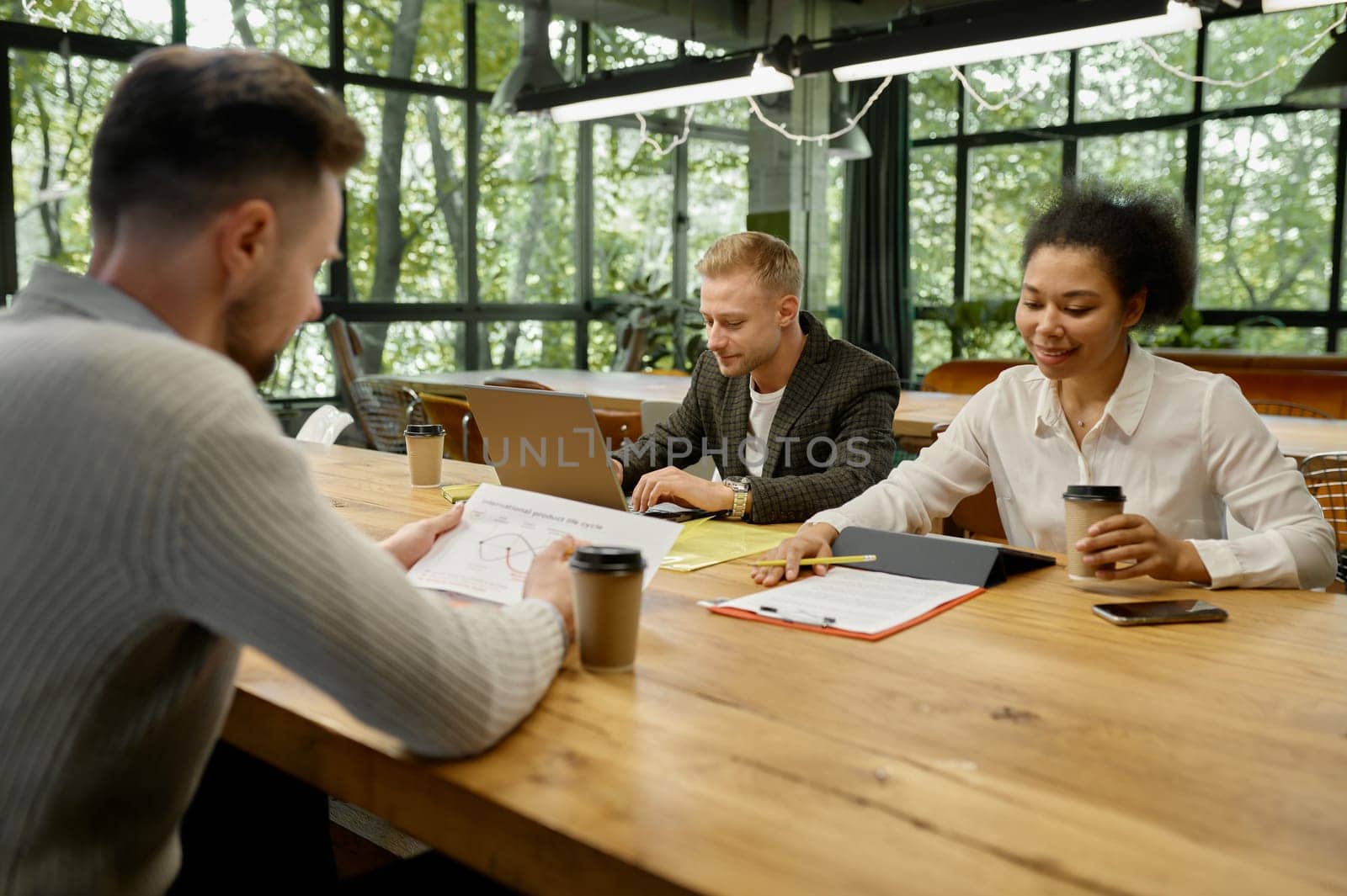 Business people using gadgets talking and smiling during team meeting in office. Colleagues collaboration concept