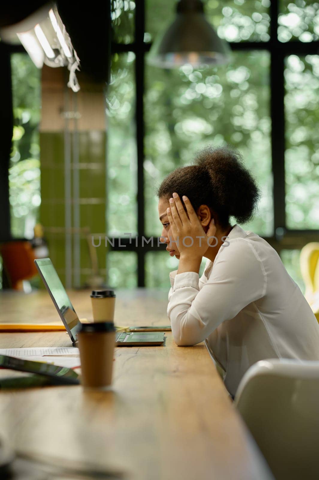 Shocked worried business woman holding head looking at laptop computer sitting at table in office room. Trouble on work, bad email notification or online project failure concept