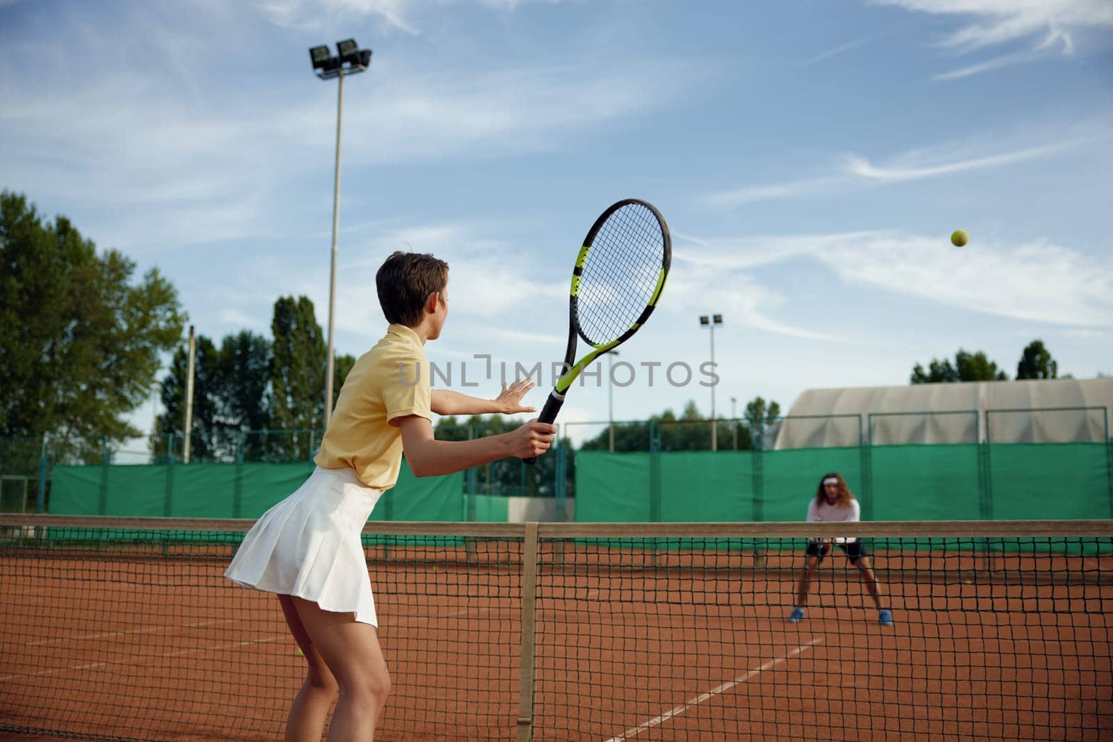 Couple of sportive friends playing tennis on court outside in evening. Leisure recreational hobby activity concept