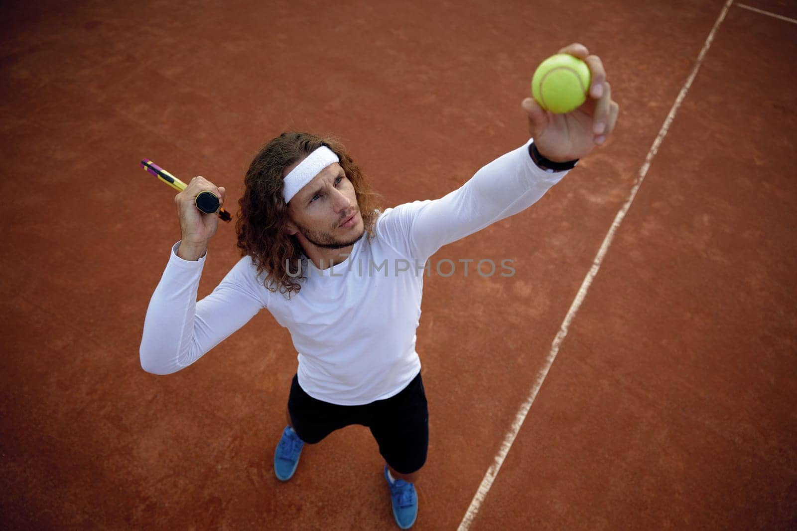 High angel view on man tennis player serving ball. Sportsman ready to hit volley enjoying interesting game match